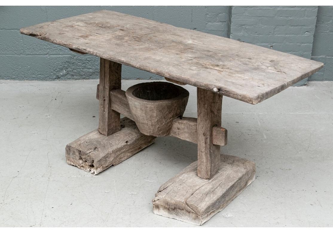 A rarely seen dynamic form in original distressed condition with great all over age and use patina. In an overall weathered finish to a pale gray tone, with some mortise and tenon construction. With a single plank top mounted on heavy block legs