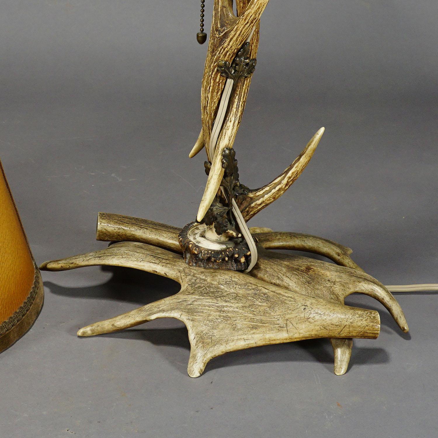 A large antler desk lamp made of deer and Virginia deer antlers, with brass decorations representing oak leaves. Manufactured circa 1920. Original antique shade (can be replaced).

Measures: height 22.44