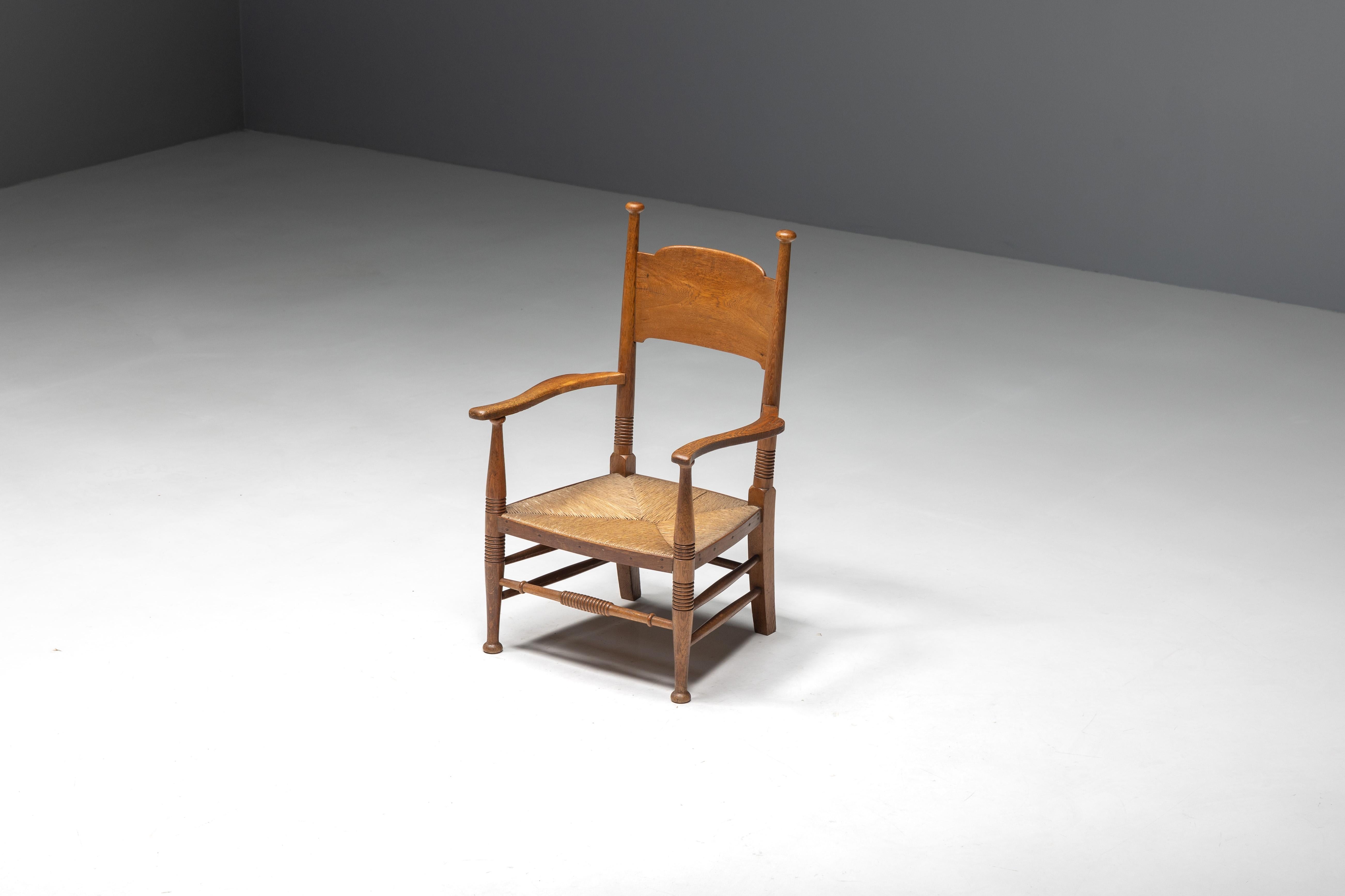 Rustikaler Sessel aus den frühen 1900er Jahren, der die außergewöhnliche Handwerkskunst britischer Kunsthandwerker im Geiste der Arts-and-Crafts-Bewegung zeigt. Der aus robustem Eichenholz gefertigte Sessel mit einer Sitzfläche aus natürlichem Stroh