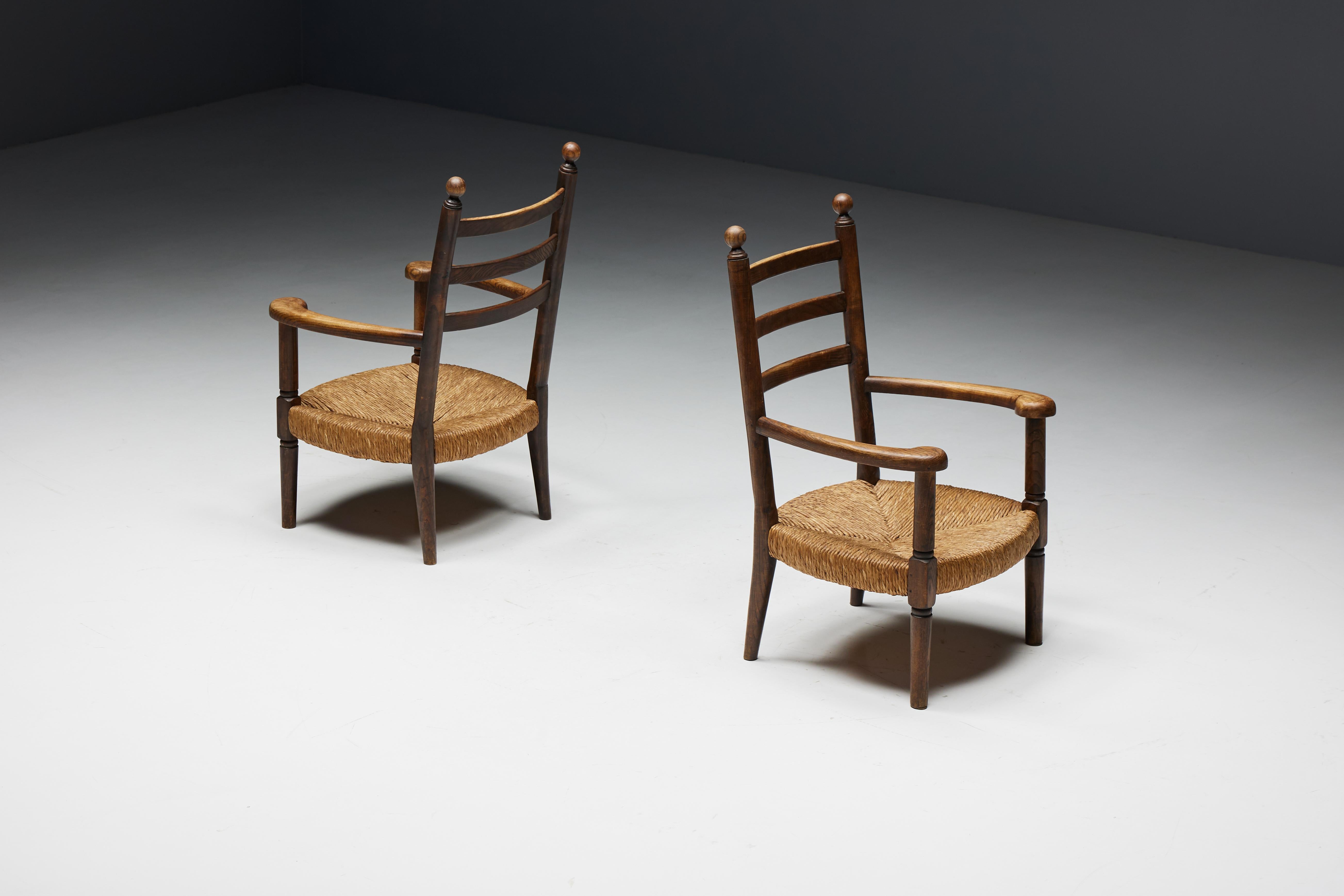 Rustikale Sessel aus den frühen 1900er Jahren zeigen die außergewöhnliche Handwerkskunst französischer Kunsthandwerker im Geiste der Arts-and-Crafts-Bewegung. Die aus robustem Holz gefertigten Sessel mit ihren aus Binsenstroh geflochtenen Sitzen