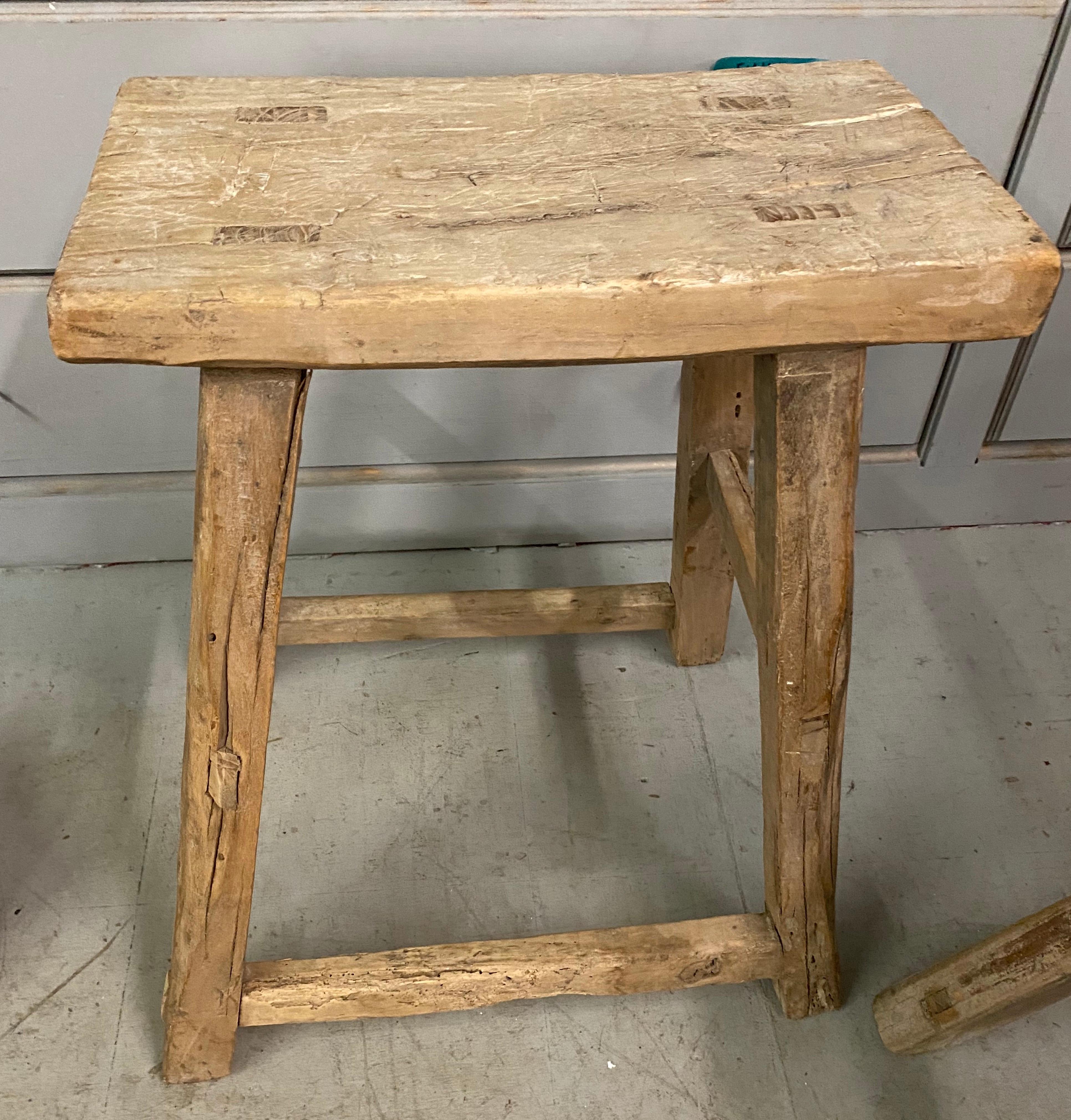 The rustic Chinese stool from the Qing Dynasty period with mortise-and-tenon joinery techniques with pegged legs that fit into the seats and stretchers that fit into the legs for sturdy construction. The stool have a balanced form and timeless