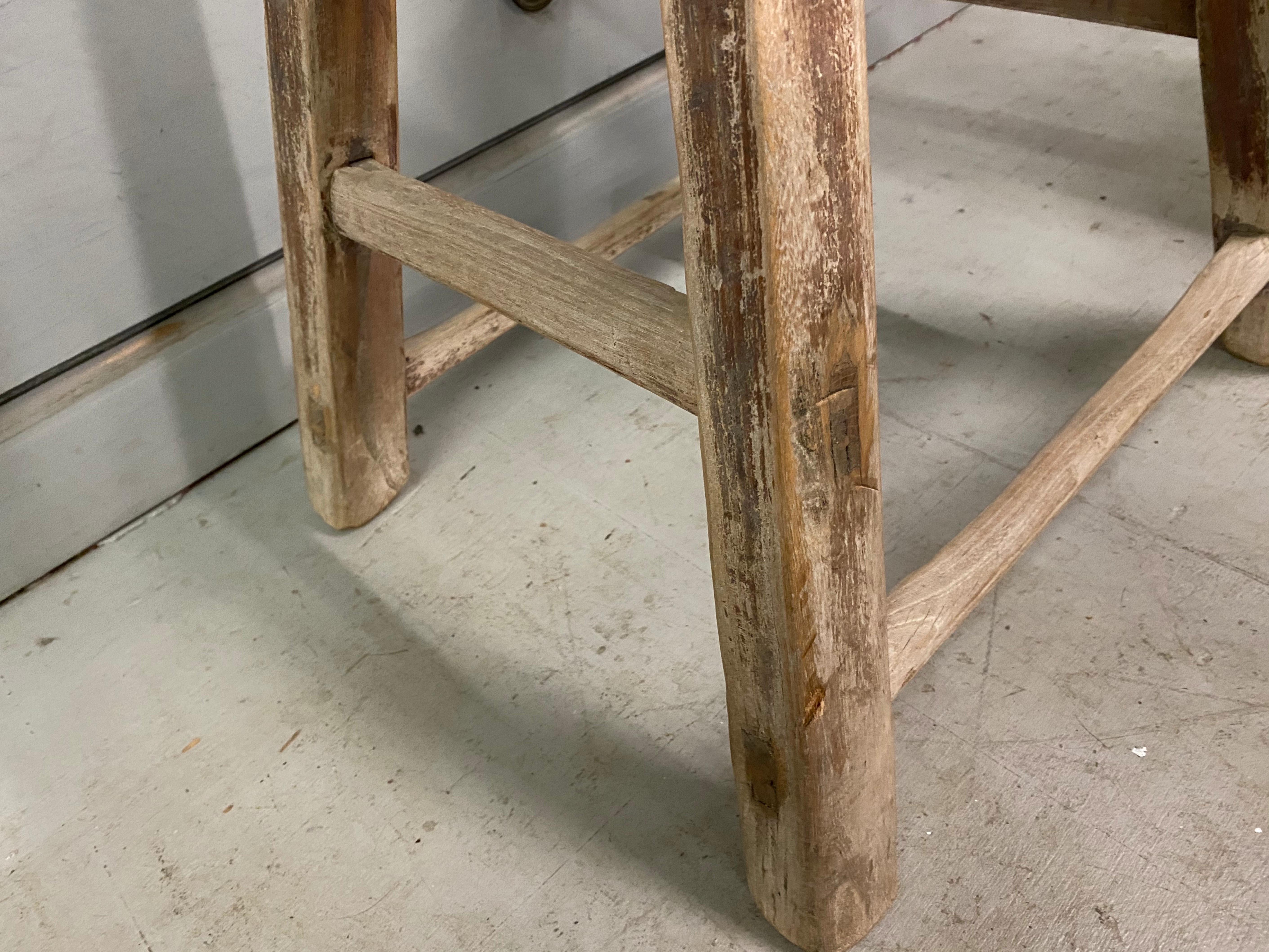 The rustic Chinese stool from the Qing Dynasty period with mortise-and-Tenon joinery techniques with pegged legs that fit into the seats and stretchers that fit into the legs for sturdy construction. The stool has a balanced form and timeless rustic