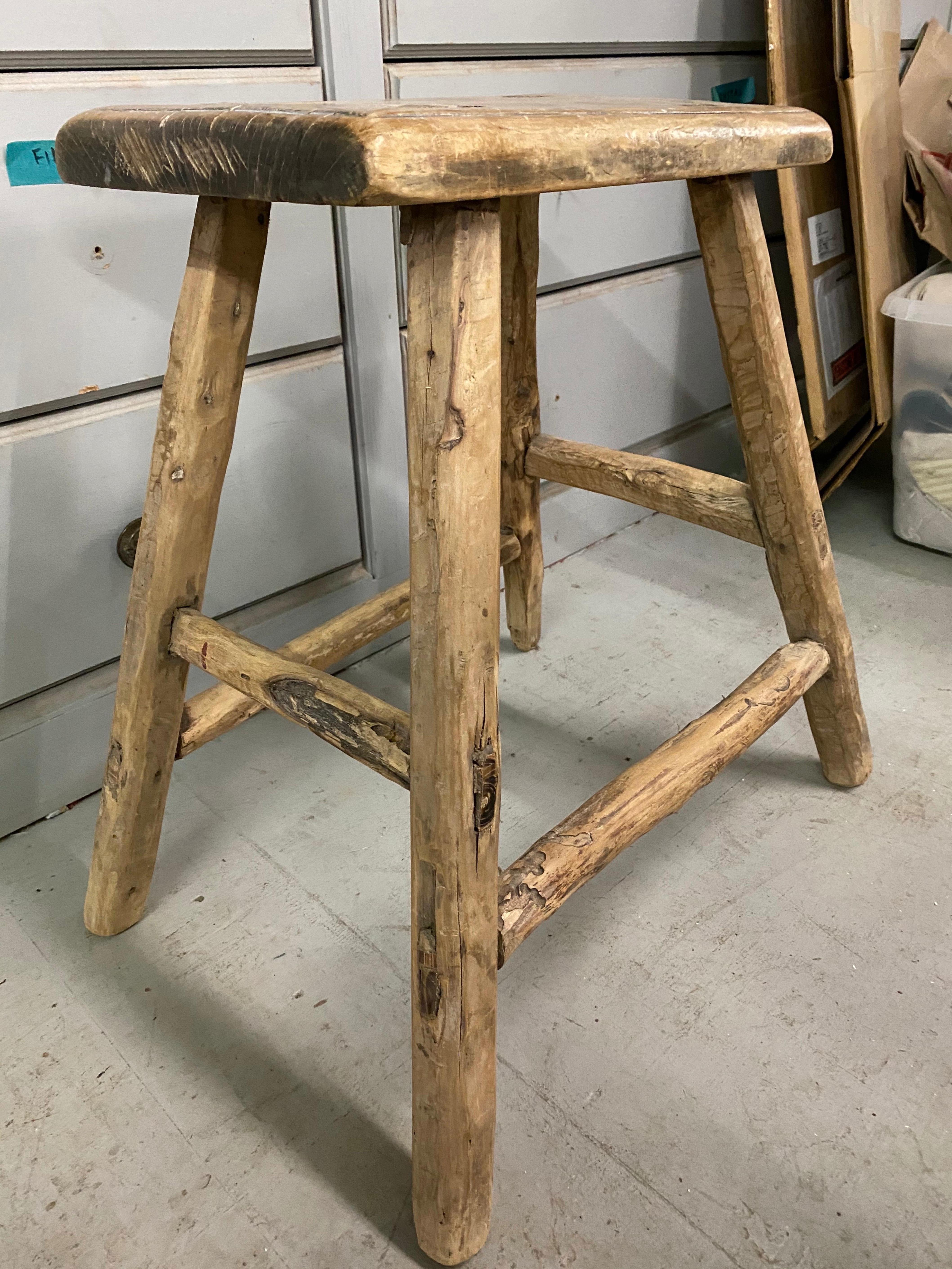 The rustic Chinese stool from the Qing dynasty period with mortise-and-tenon joinery techniques with pegged legs that fit into the seats and stretchers that fit into the legs for sturdy construction. The stool have a balanced form and timeless
