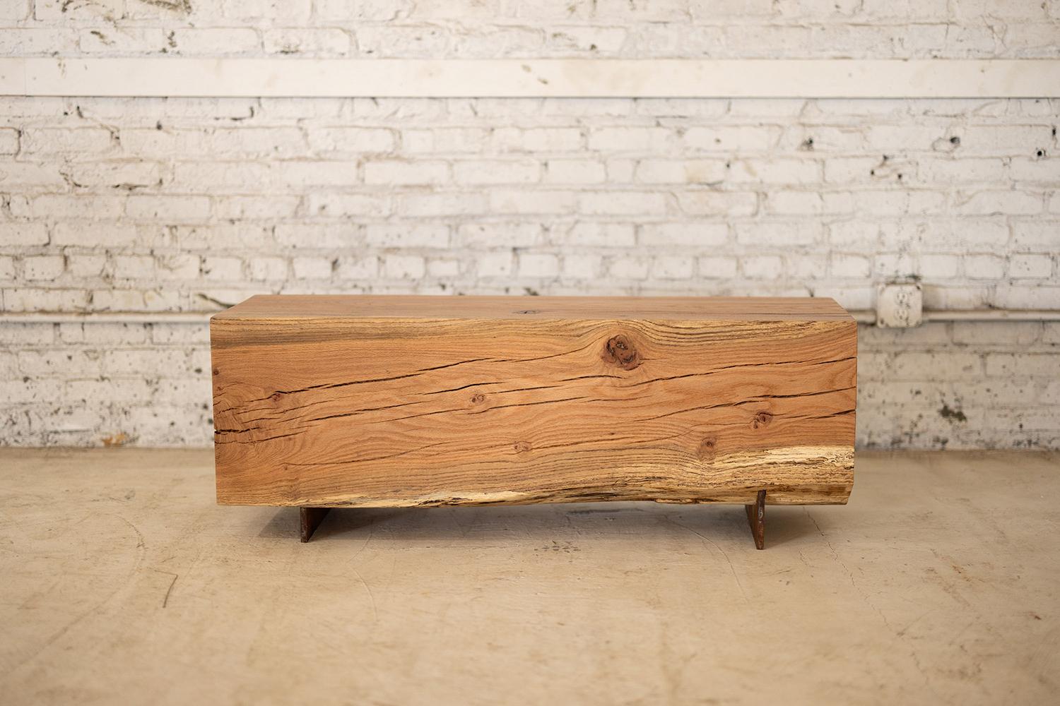 Experimenta el encanto rústico de nuestro Banco de Vigas de Madera, fabricado con diversas especies de madera autóctona y con un diseño estrecho y sin respaldo. Las líneas sencillas resaltan la textura única de la veta, mientras que la base de acero