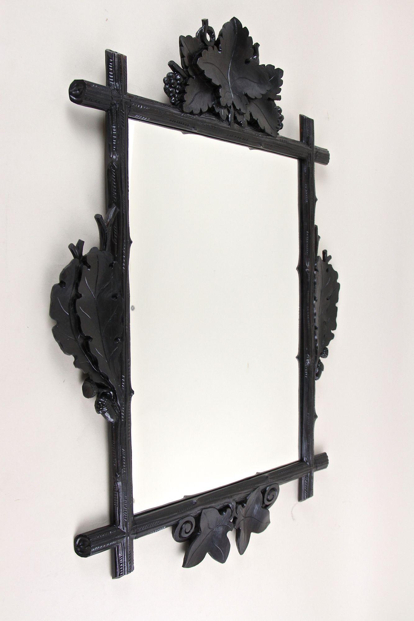 Eccezionale specchio da parete Black Forest con intagli di foglie di vino, Oak e edera, risalente al periodo intorno al 1890 in Austria. Questo specchio da parete rustico di fine Ottocento dal design fantastico colpisce per la sua cornice in stile