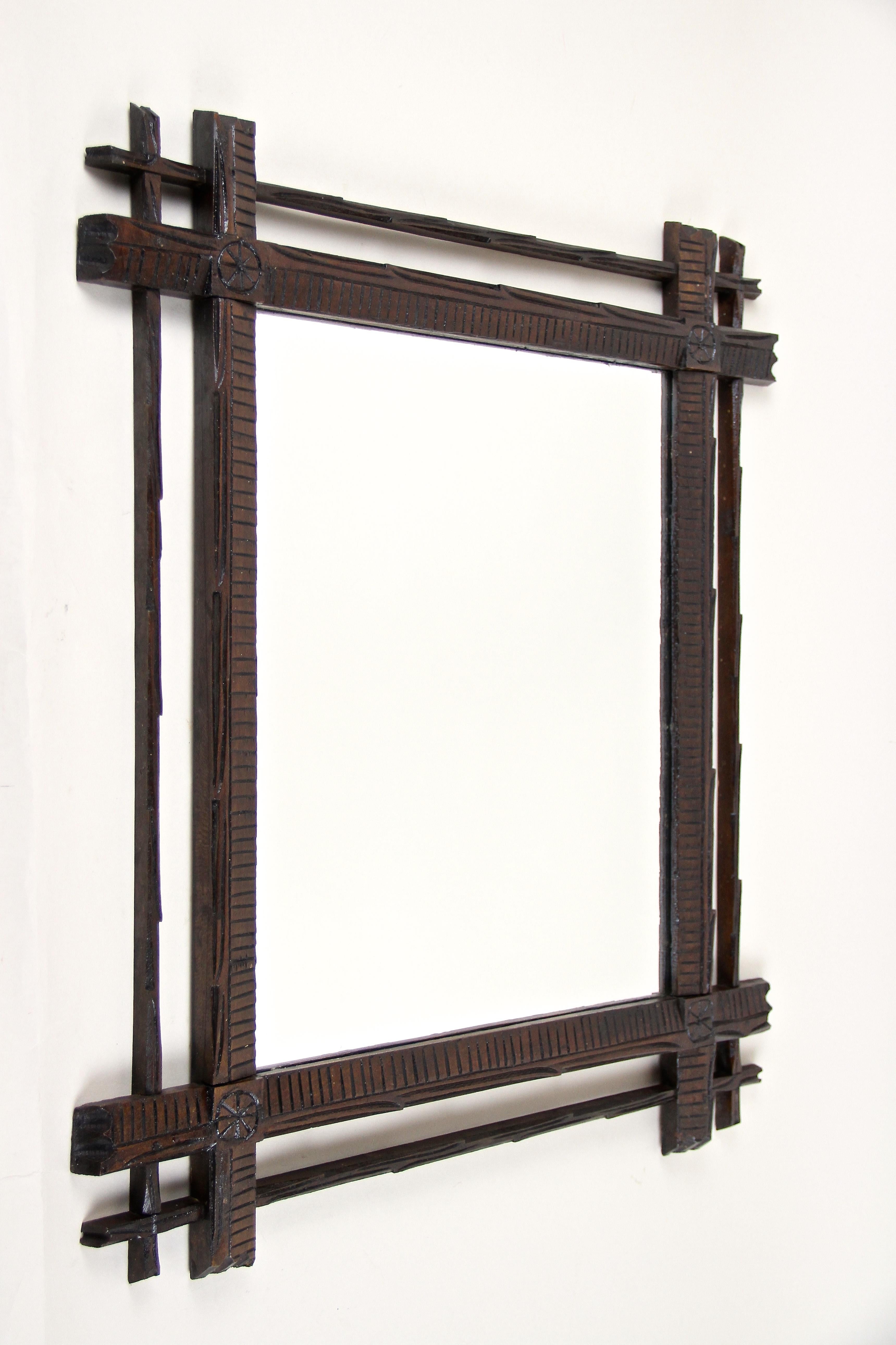 Unusual hand carved Black Forest wall mirror with double frame out of Austria around 1880. A charming piece of a rustic Black Forest mirror, elaborately hand carved out of basswood, showing a very dark brown stained surface. Framed by slim bars in