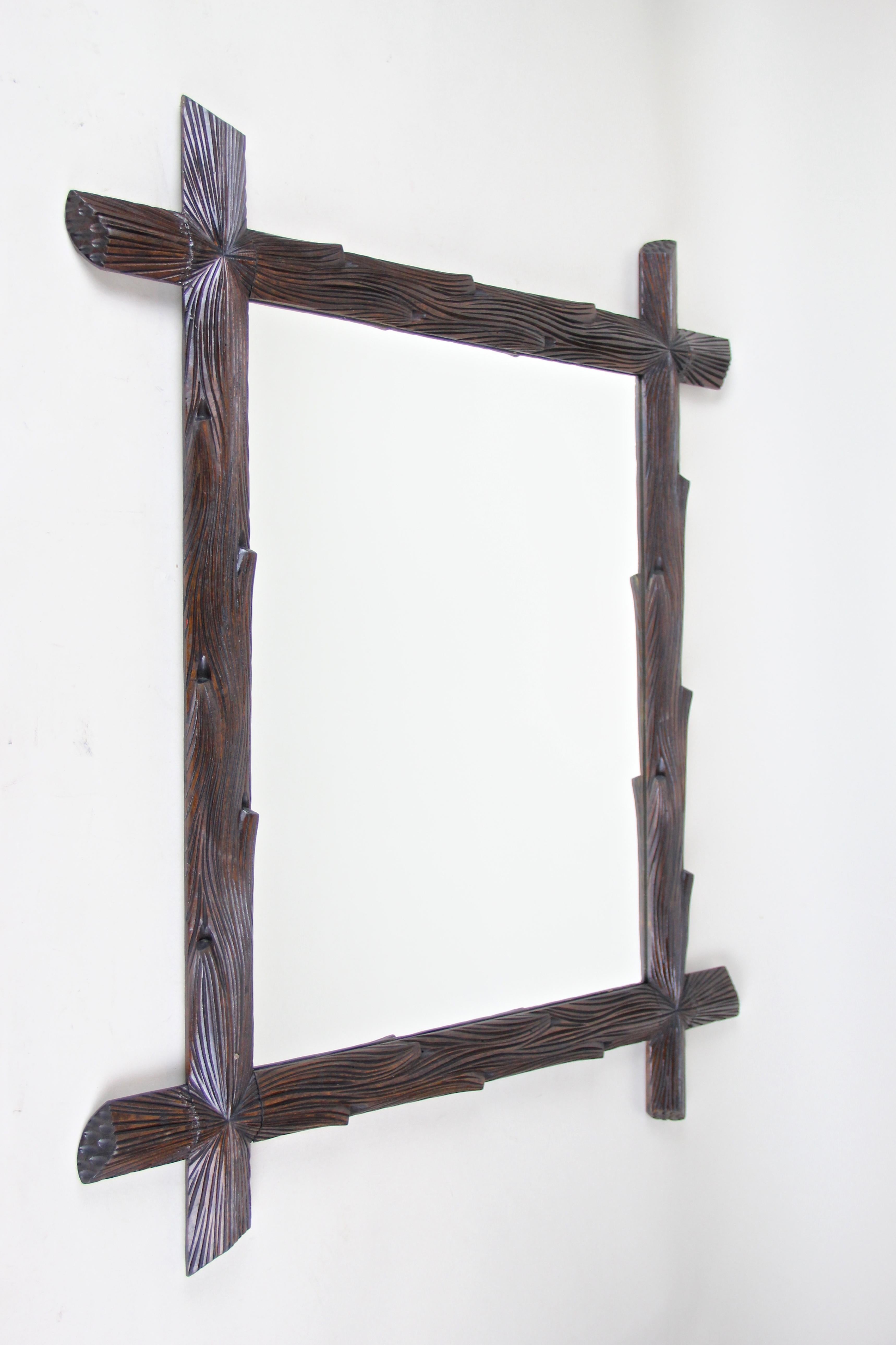 Mesmerizing Black Forest wall mirror from Austria circa 1890. This rustic wooden mirror has been elaborately made out of basswood in the manner of tree branches and impresses with its unique radial carved corners. The beautiful darkbrown nearly