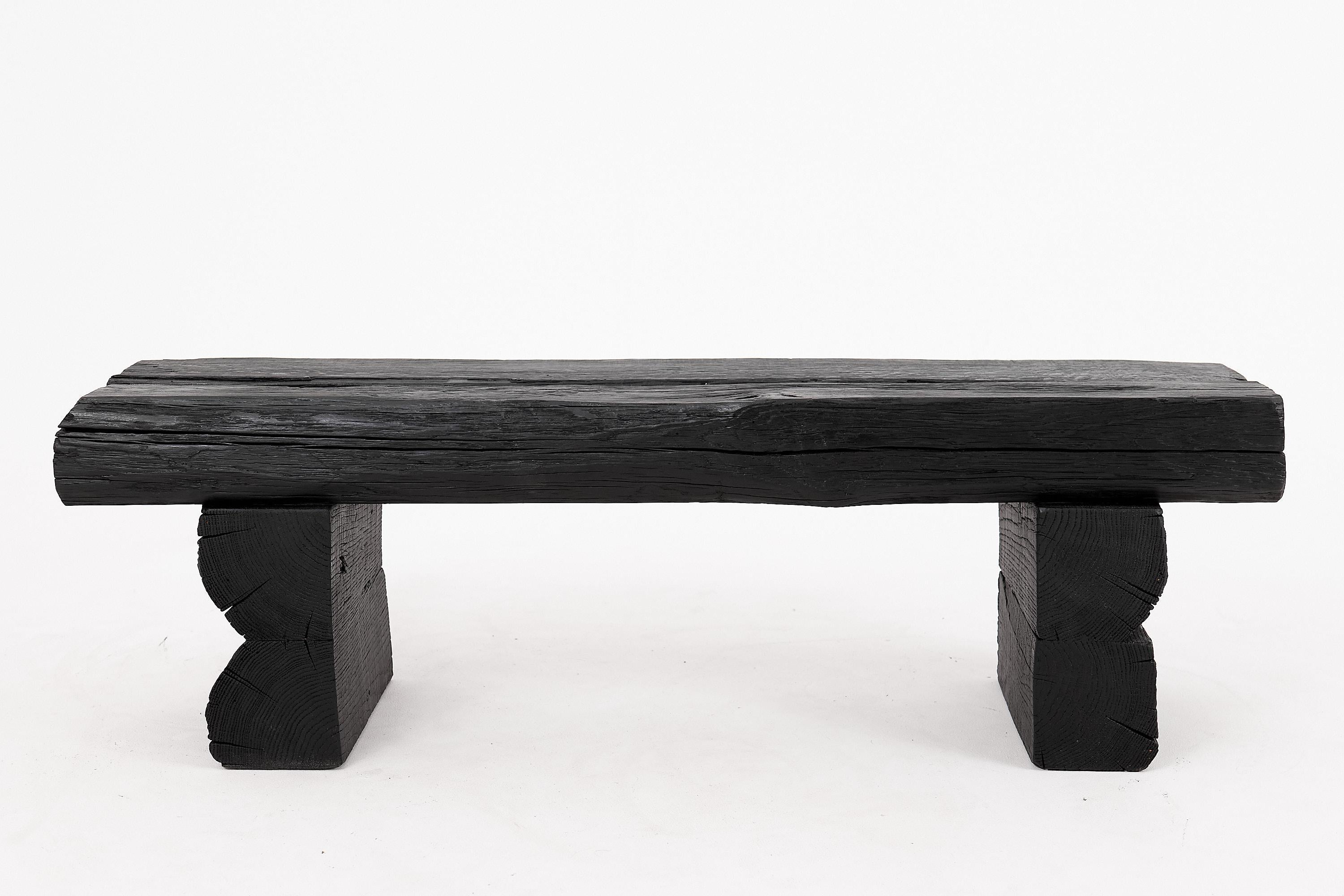 Questa splendida panca in legno annerito emana un'estetica grezza e organica, che unisce il fascino rustico al minimalismo contemporaneo. Realizzata con travi di legno di quercia recuperate, la panca presenta una superficie dalla texture