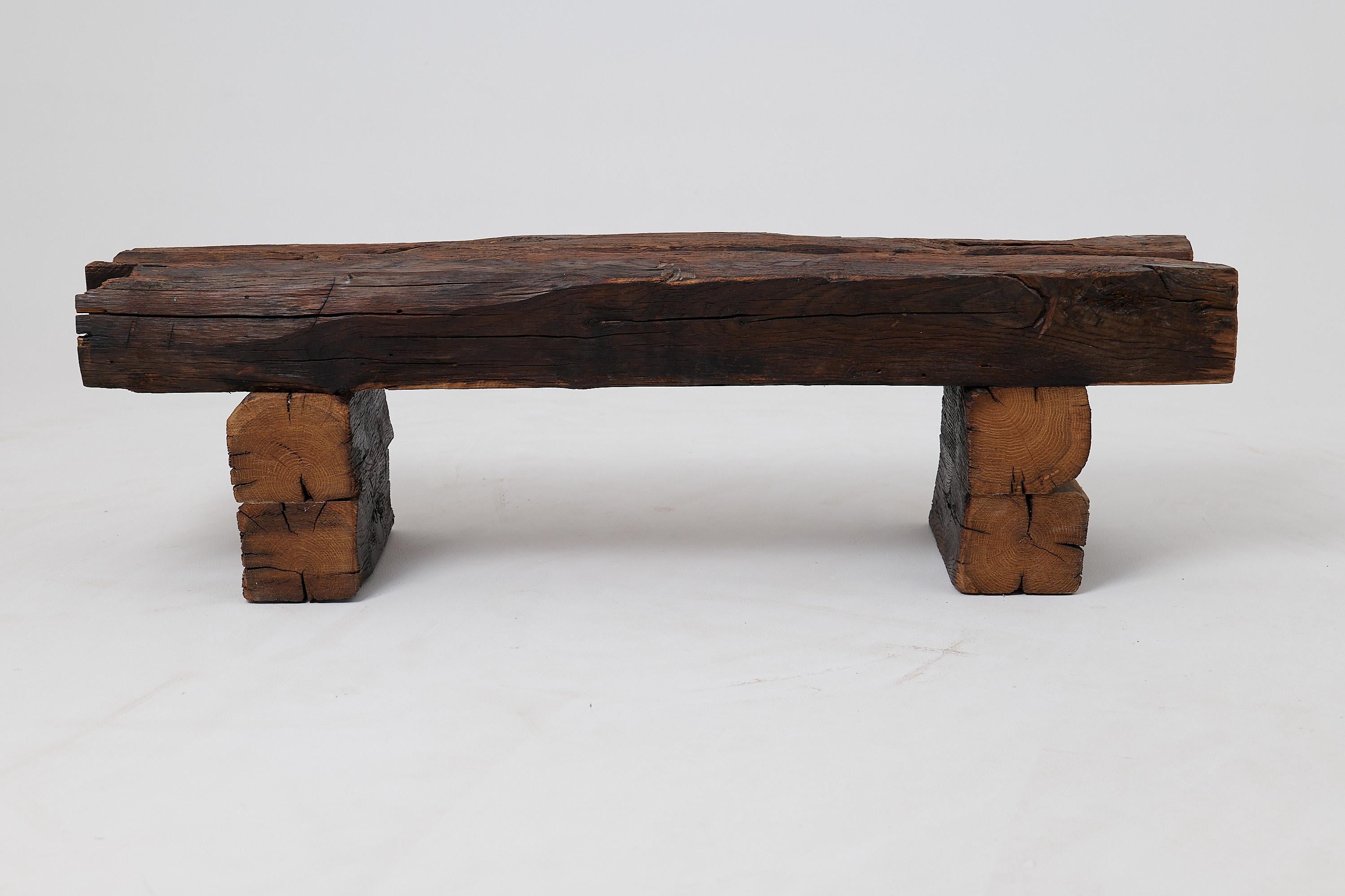 Ce banc architectural est une pièce unique, fabriquée à partir de poutres massives en chêne récupéré, vieilles de plus d'un siècle. Sa forme est une déclaration puissante de design minimaliste, où l'immense histoire du bois lui-même est l'élément