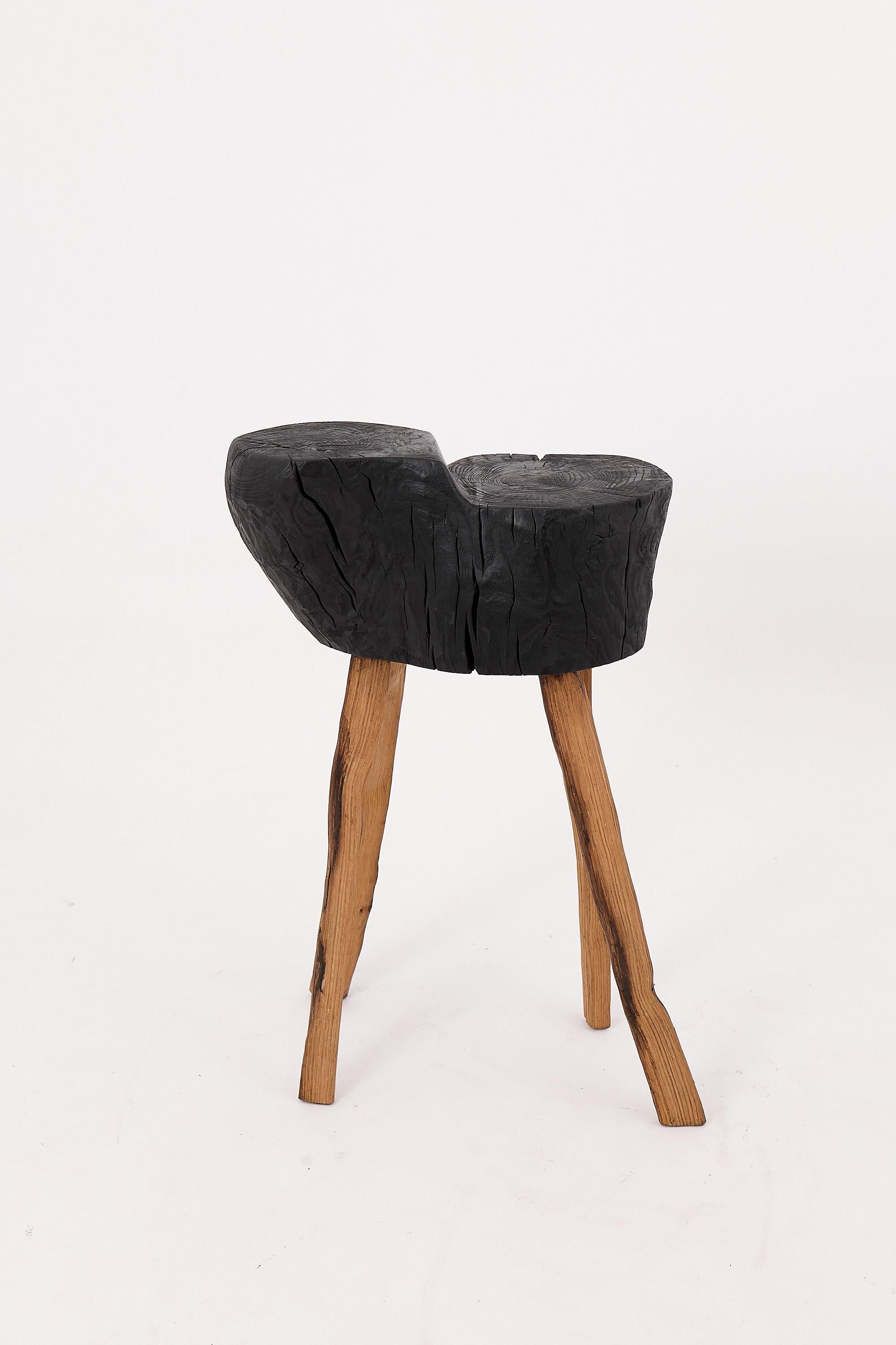 This sculptural side table is a one-of-a-kind work of functional art, carved by hand from a single hardwood log and charred using the traditional shou sugi ban technique. Its organic form feels discovered rather than constructed, with contours