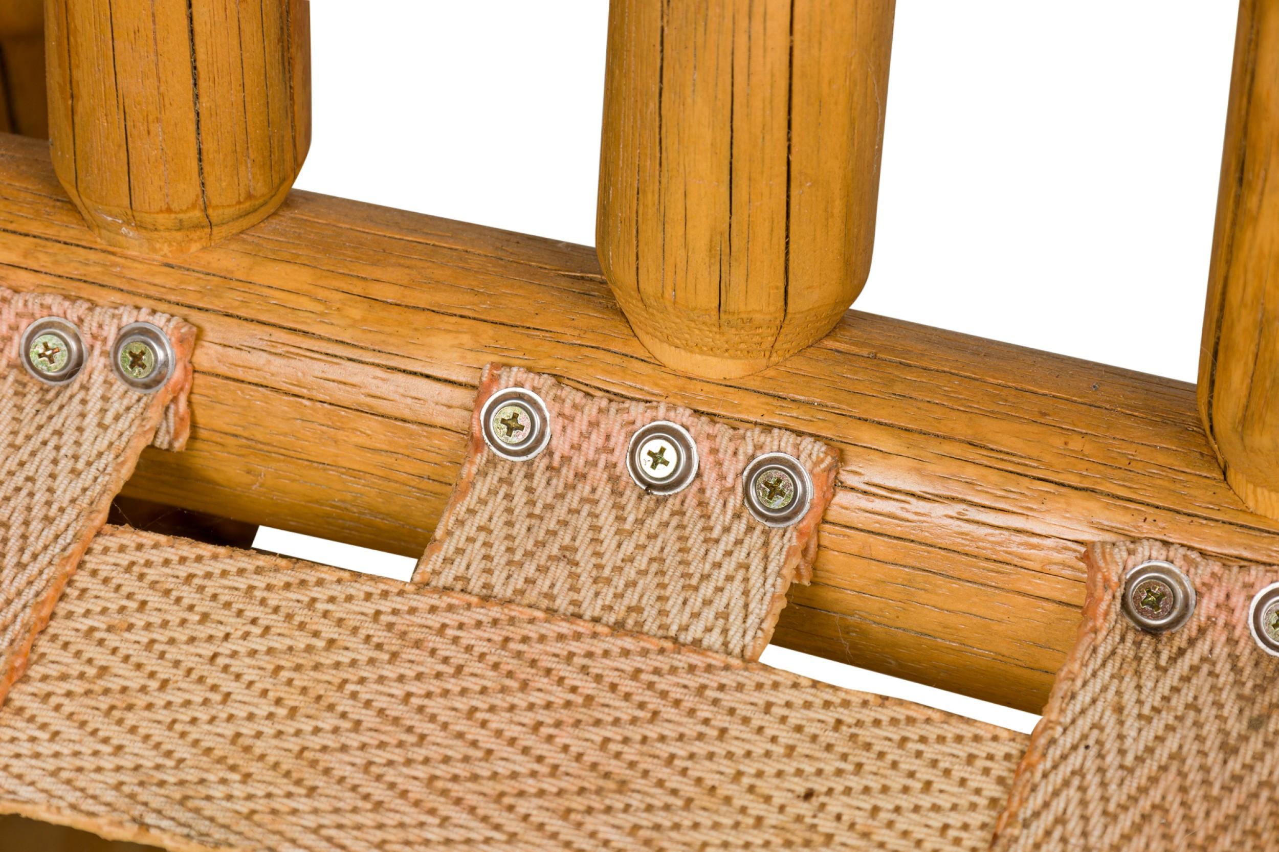 Fauteuil rustique de style Adirondack surdimensionné avec une structure en bois de racines blondes, un dossier en angle avec des lattes verticales en bois rond et un coussin d'assise et de dossier amovible en cuir brun caramel gaufré et fleuri.
