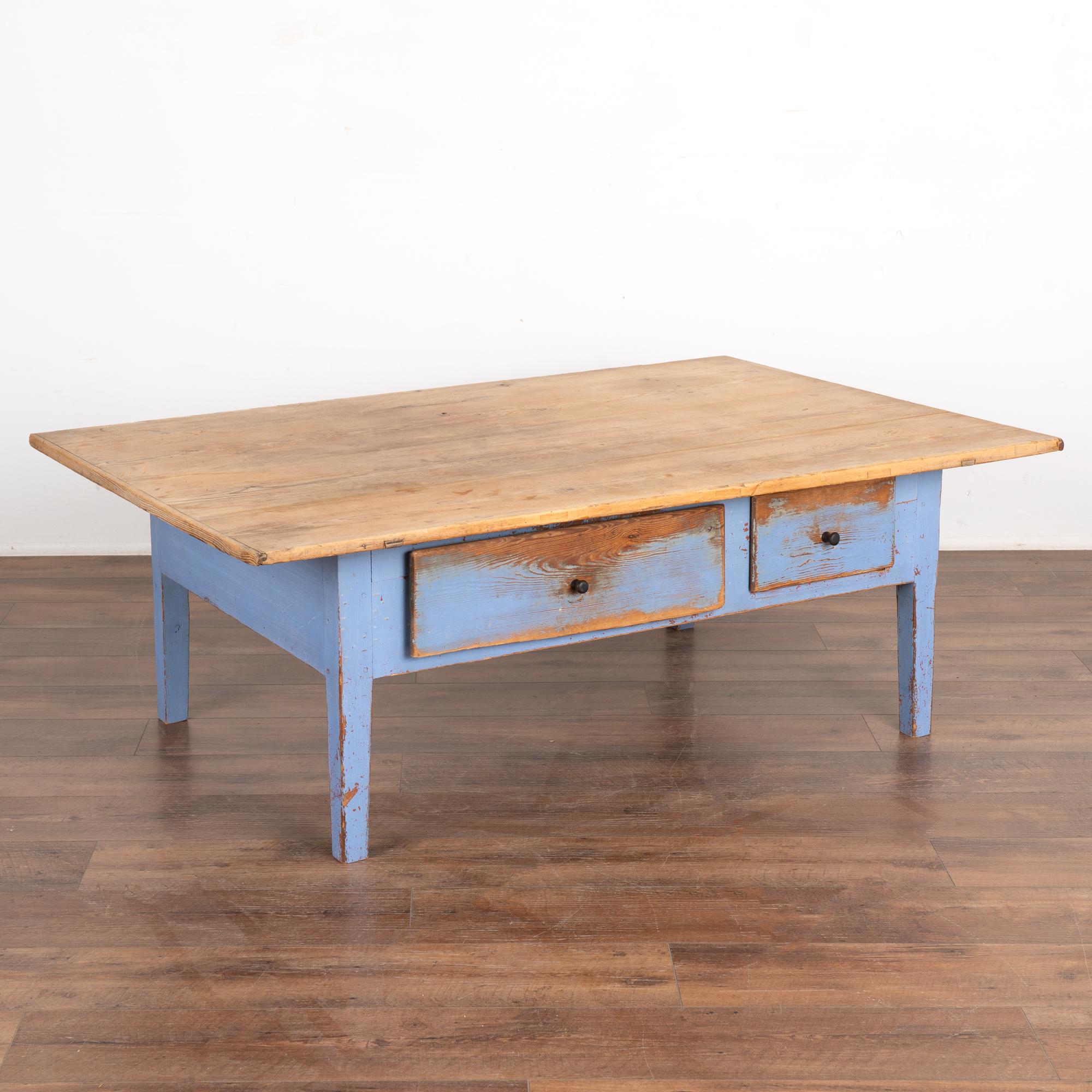 The rustic appeal of this coffee table comes from the aged patina of the pine wood top which contrast with the cheerful blue painted base.
Every scratch, nick, crack and stain simply add to the draw of this coffee table with two drawers. Note how