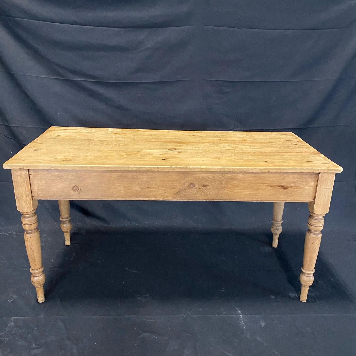 A beautiful antique multi use scrubbed pine British table, desk, console, or kitchen prep table. The table is in wonderful condition with a traditional plank top and retains the original scrubbed pine finish with beautiful patina. The base is of