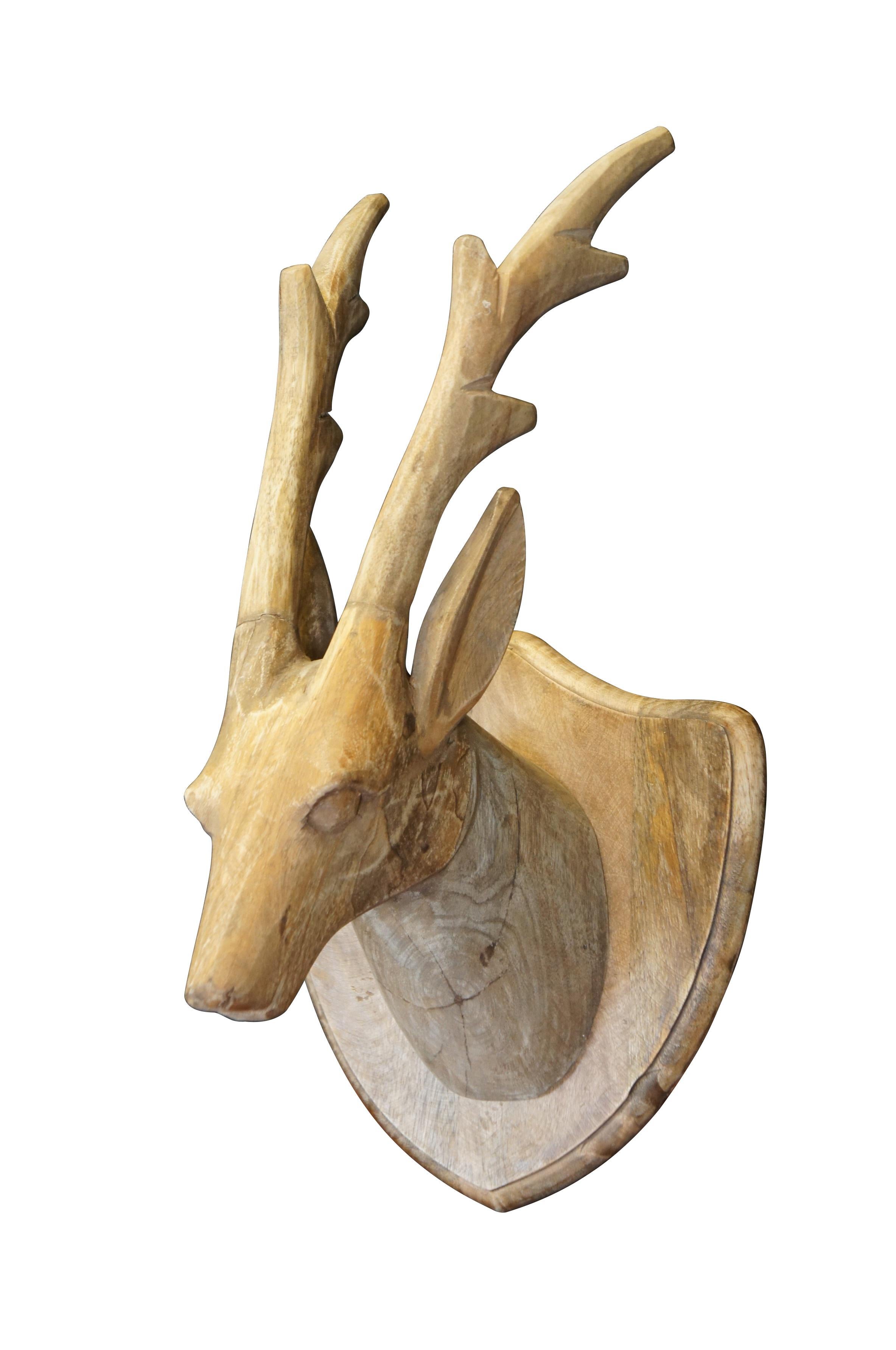 Late 20th century plain hardwood carved country / farmhouse / rustic deer / antelope head with slender four point antlers, set on a shield shaped wall hanging plaque.

Dimensions:
10.25