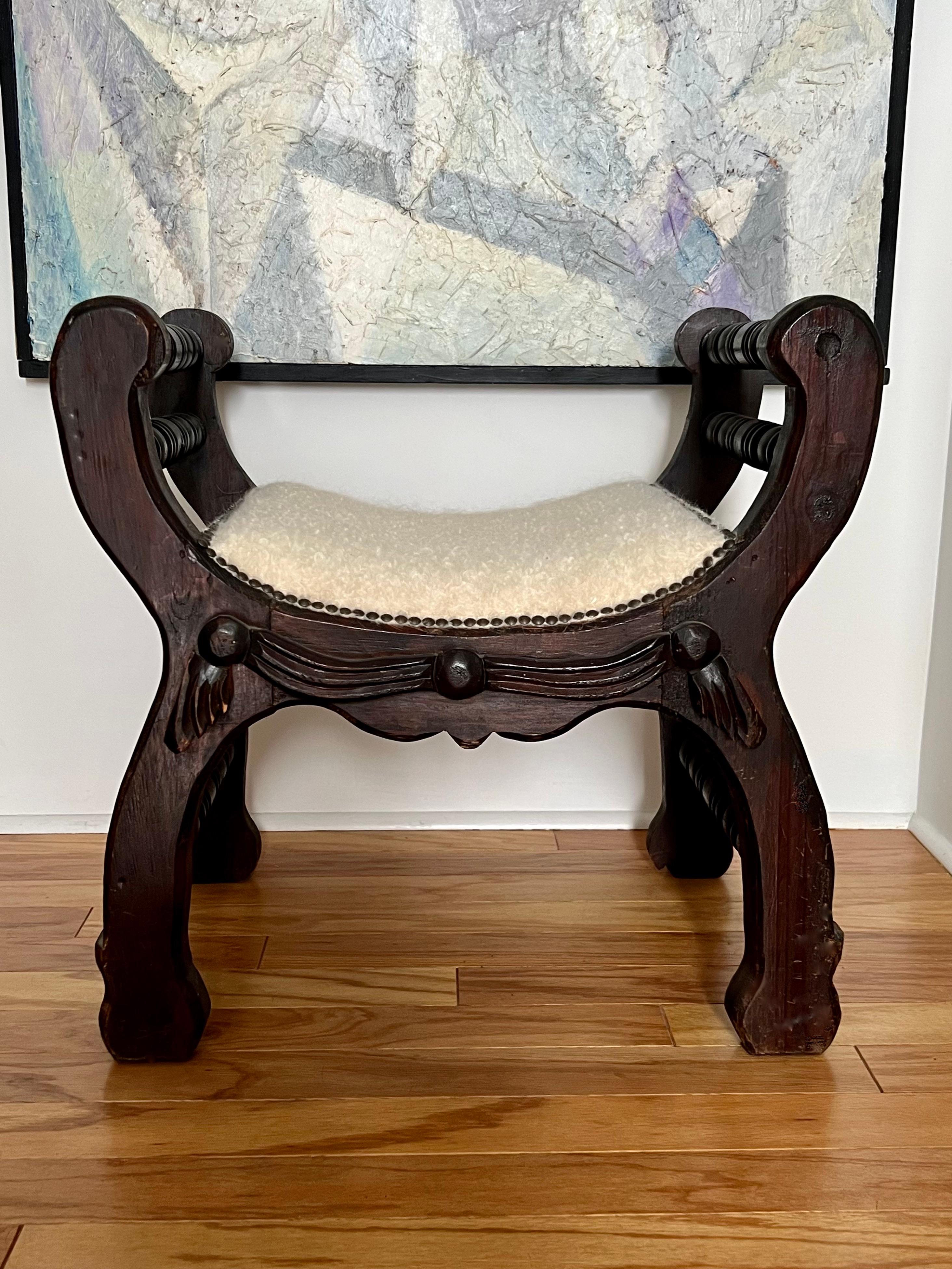 Mexican rustic carved wood bench with spool-turned crossbars. Newly upholstered in La Maison Pierre Frey's most luxurious boucle, Louison Creme, which sells for over $700 a yard. The bench features the original dark brown finish, now distressed
