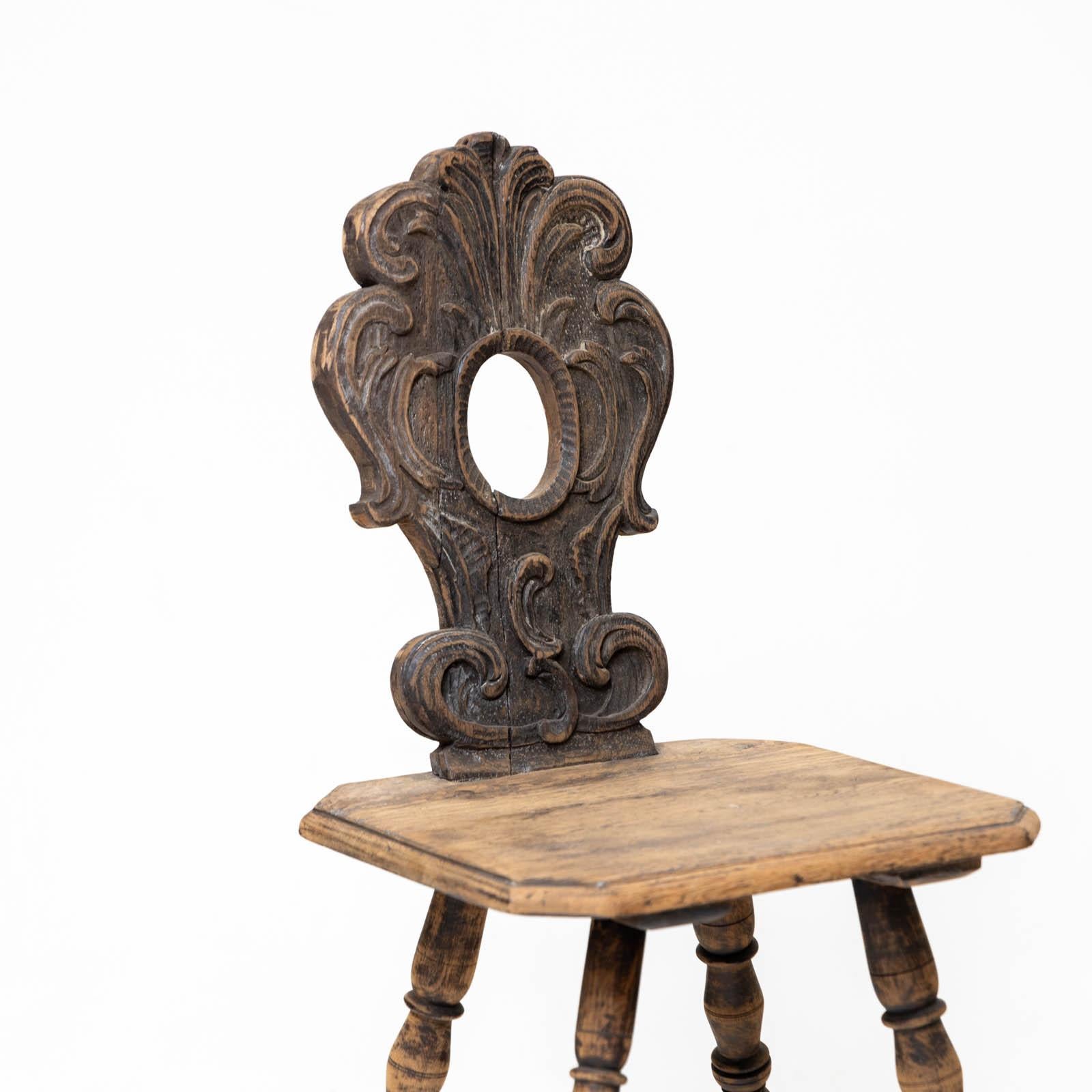 Rustic oak chair with an octagonal seat and turned legs. The backrest has an oval cut-out with carved rocailles.