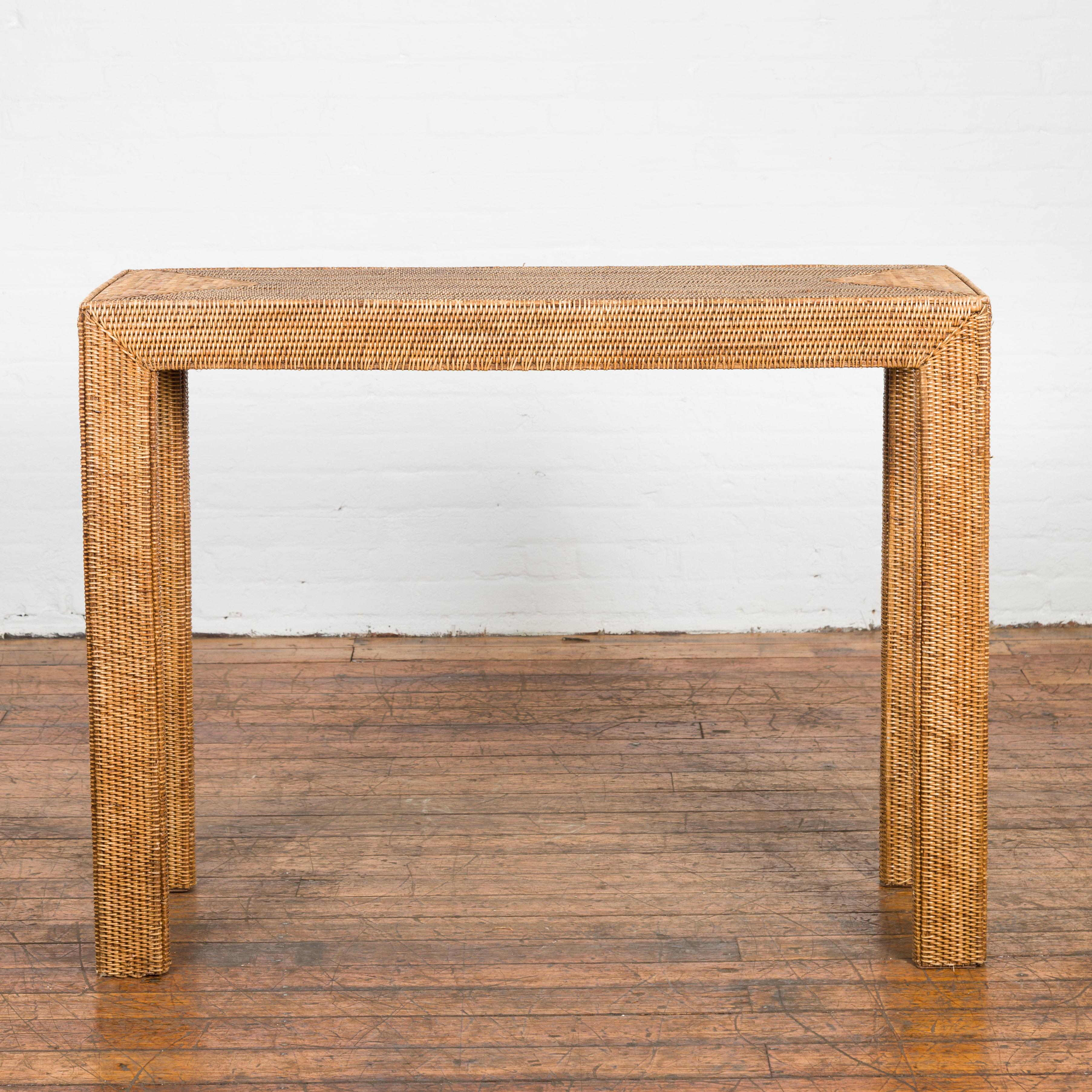 Midcentury Style Woven Rattan Console Table from the Mid-20th Century, with straight legs and triangular patterns. Created in Burma during the midcentury period, this console table charms us with its simple silhouette and rustic character. The table