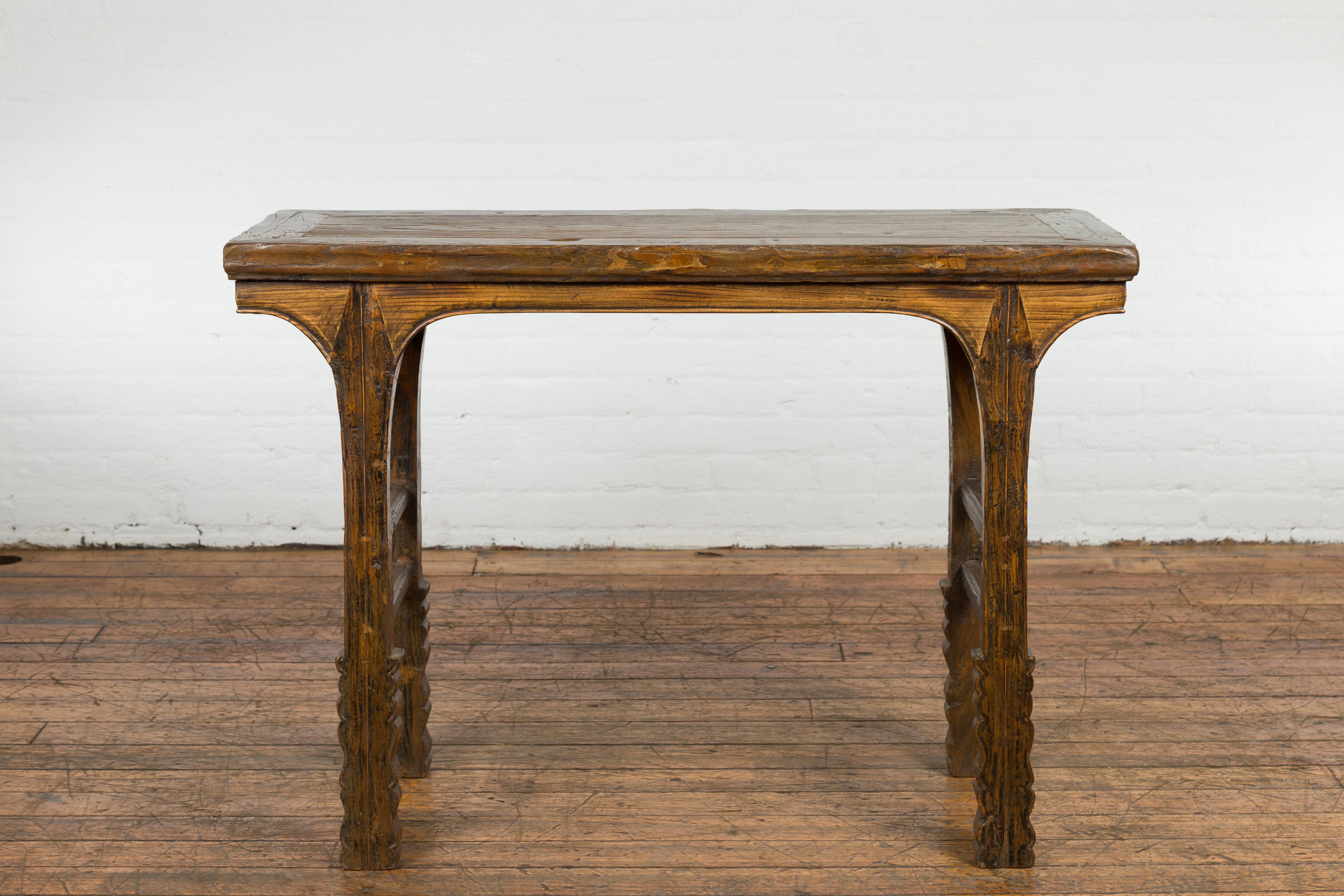 A Chinese Qing Dynasty period rustic console table from the 19th century with carved legs and double side stretchers. Welcome to the realm of rustic charm with this Chinese Qing Dynasty period console table. A relic from the 19th century, this table