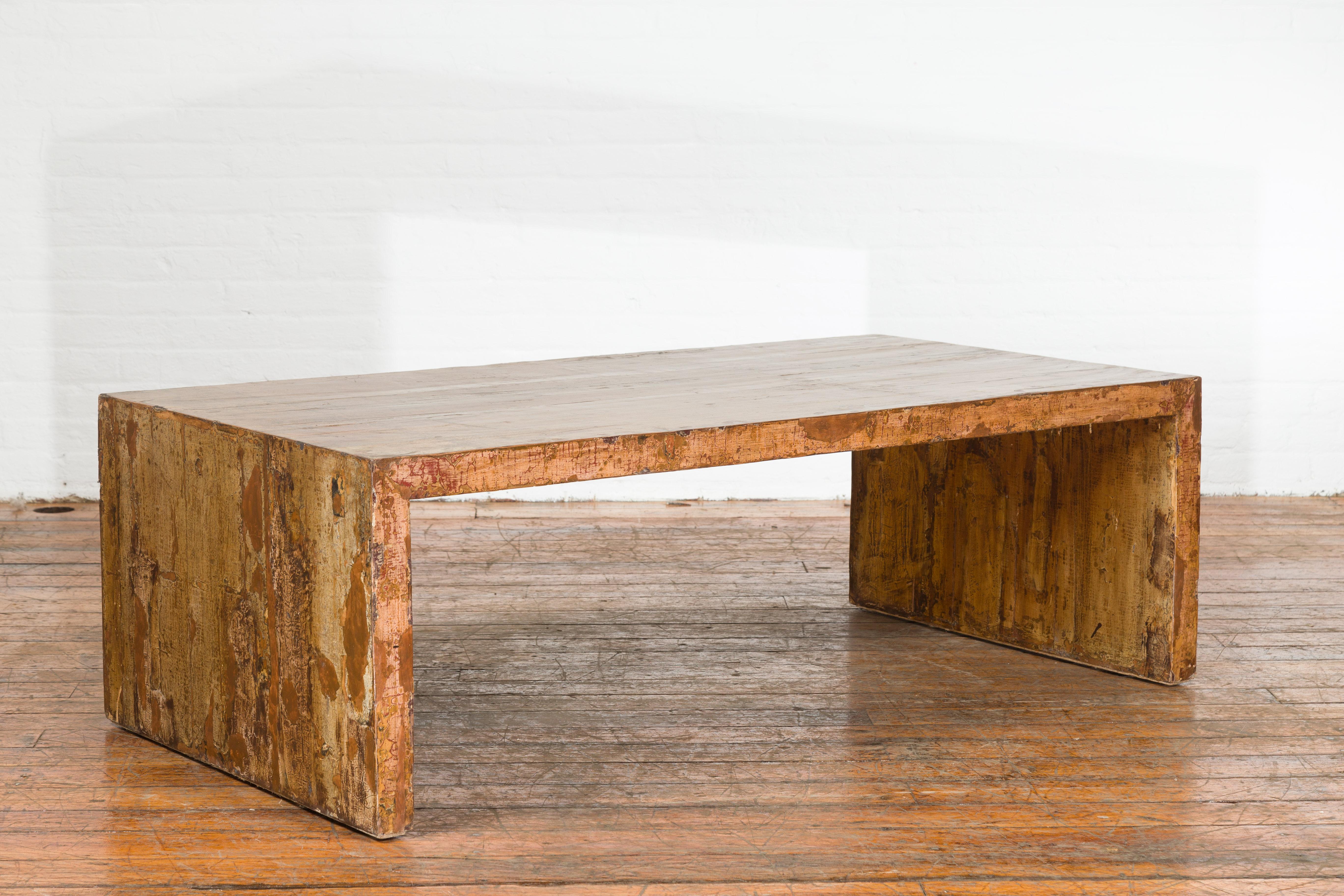 A Chinese rustic vintage coffee table from the mid 20th century, with distressed patina. Created in China during the midcentury period, this vintage coffee table features a linear silhouette perfectly complimented by a nicely weathered finish. With