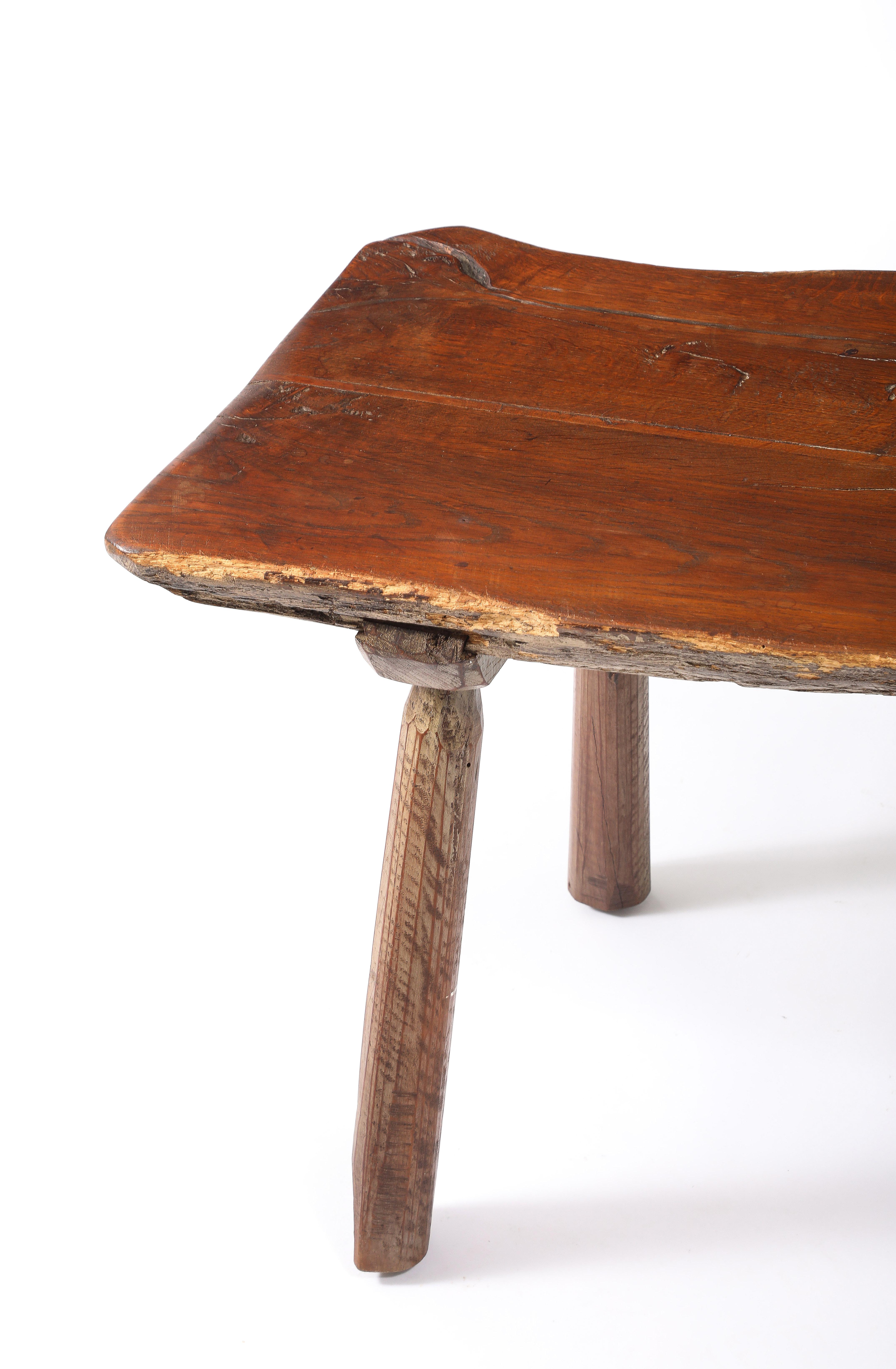Table basse rustique sculptée à la main avec un bord vif sur des pieds évasés.