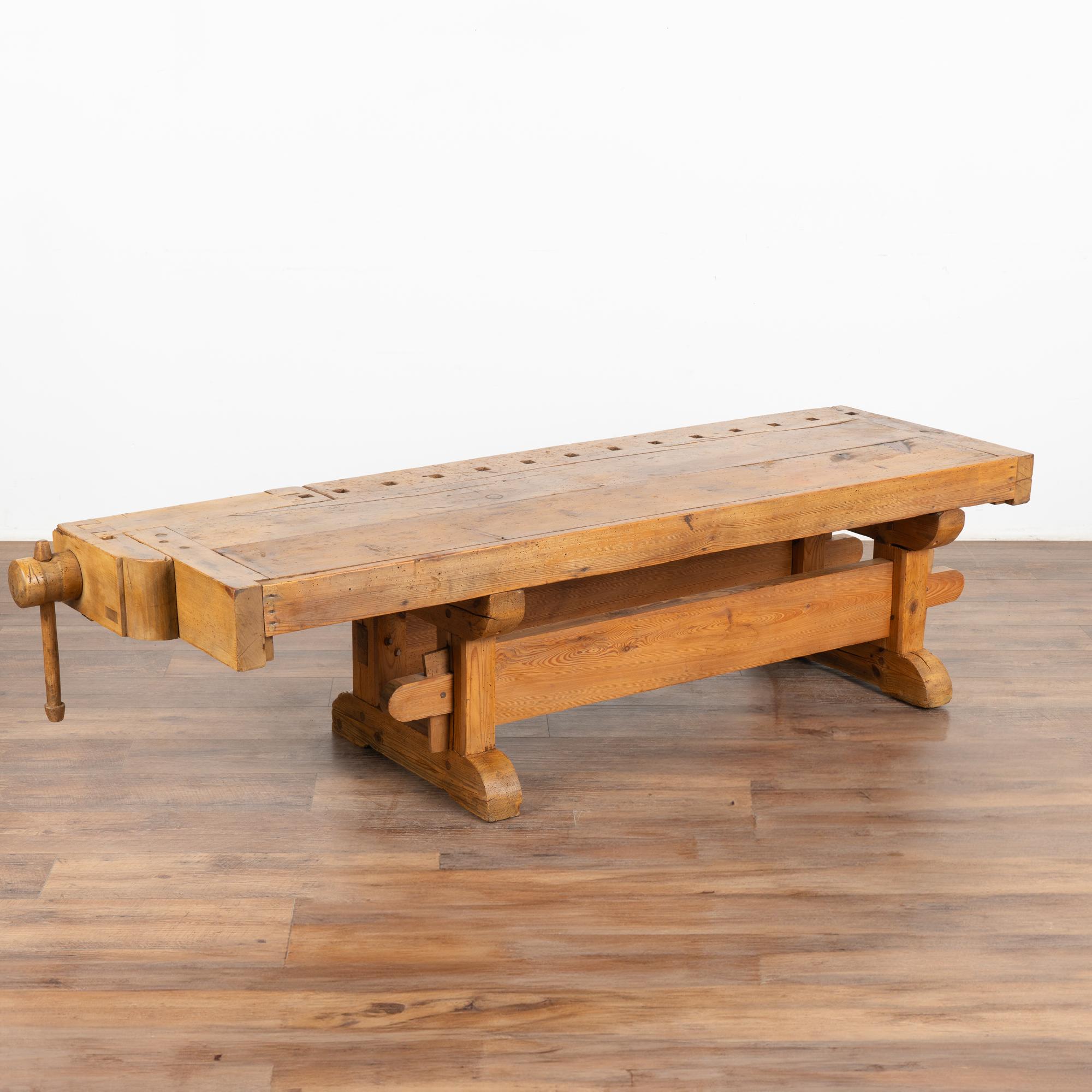 This rustic coffee table is a rare find. It was formed from a large, old carpenter's workbench and scaled down to coffee table height. 
It is the years of constant use revealed in every ding, gouge, cracks, old dried worm hole and stain that enrich