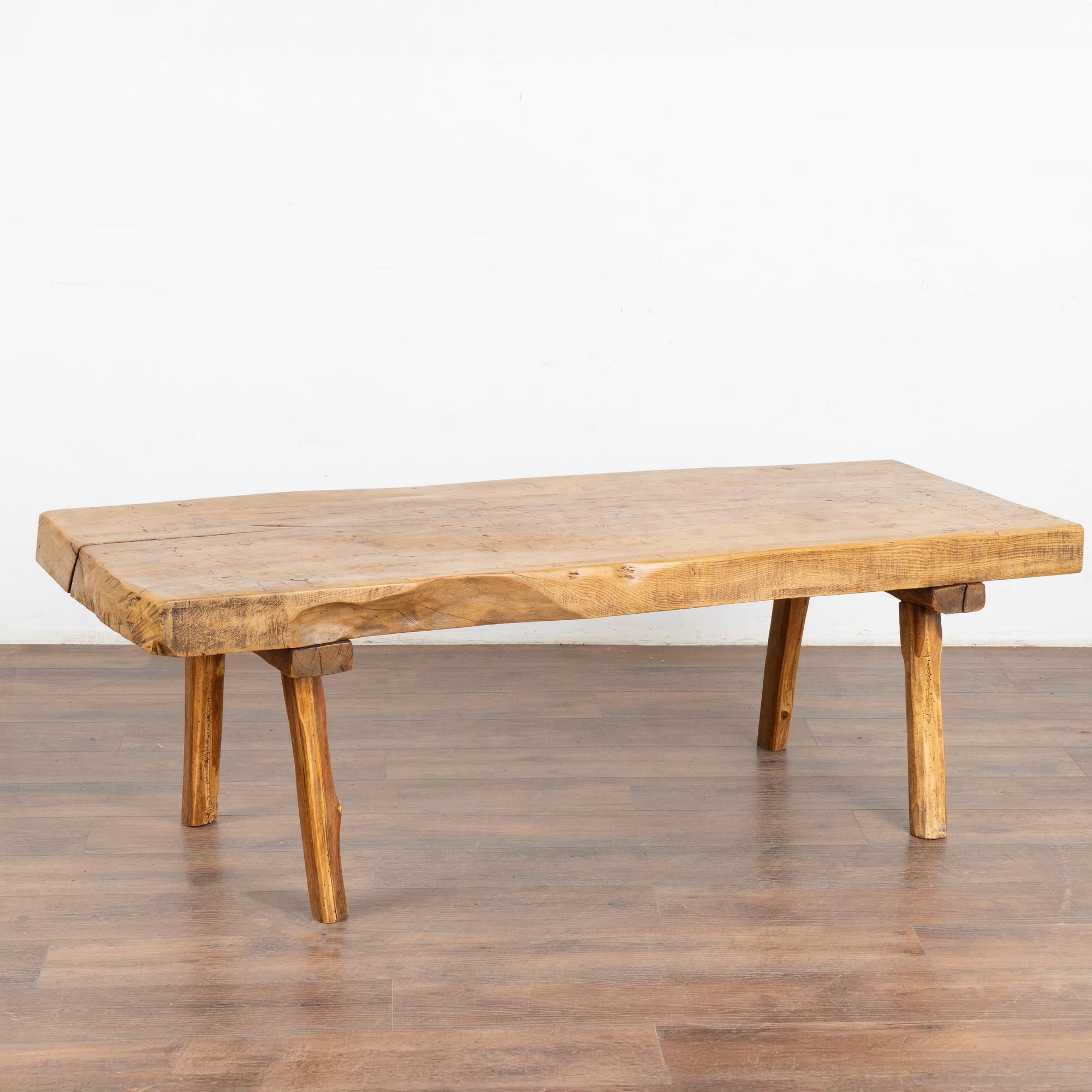 The appeal of this rustic coffee table comes from the thick wood of the top that originally served as a work table, all resting firmly on peg legs.
The slab of wood that serves as the top is impressive with the deep gouges, stains, scrapes and even