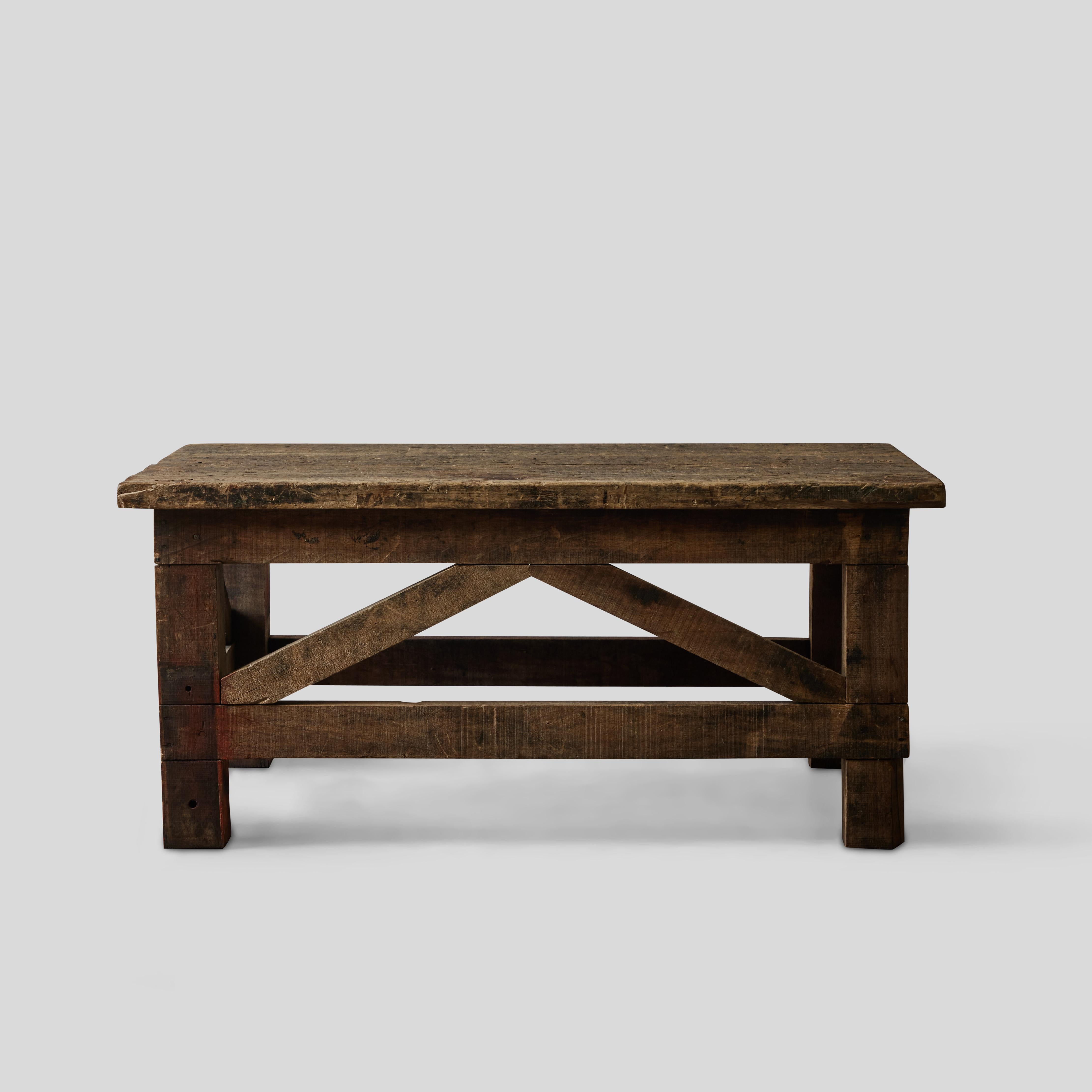 French 1860s rustic wooden coffee table. Extremely versatile, this 19th-century piece brings an air of bucolic, time-worn simplicity to any space. A light wash of red paint on the length of the table's vertical siding gives it an arty, cheerful