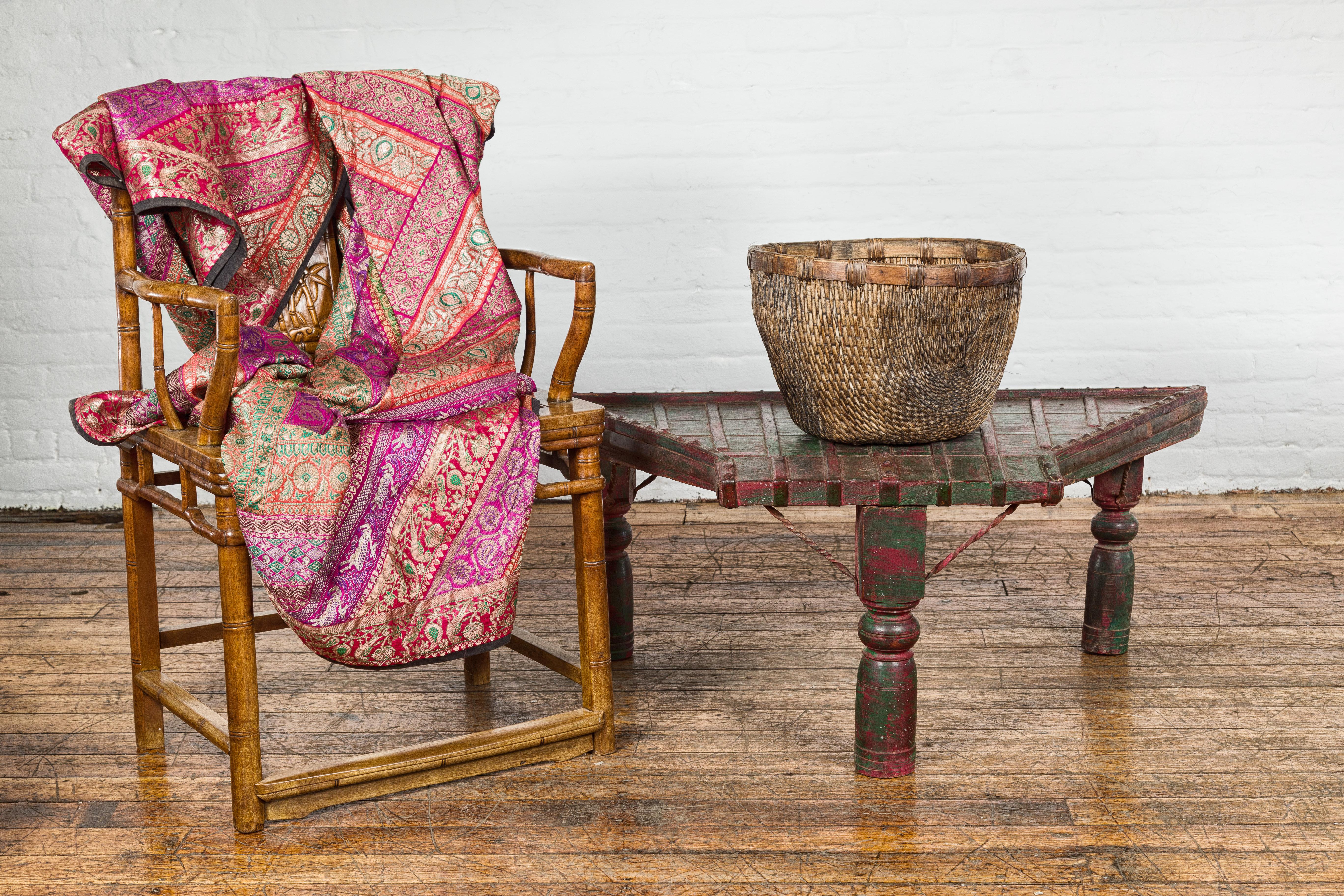 An antique rustic green and red painted coffee table crafted from a repurposed bullock cart from the 19th century with trapezoidal top, protruding front,  diamond shaped studs, twisted iron stretchers, turned baluster legs and nicely weathered