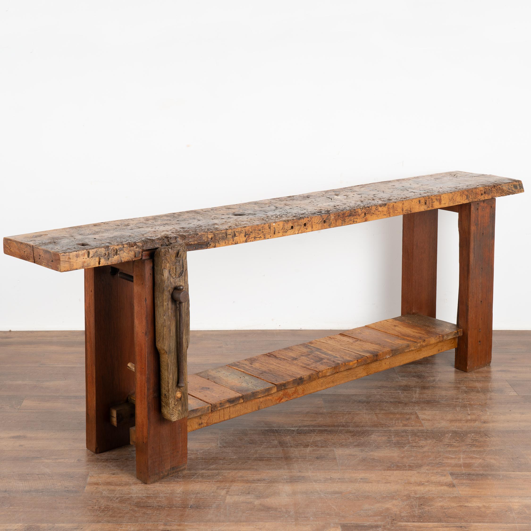Antique French carpenter's workbench rustic console table with lower shelf.
The years of constant use are revealed in every ding, gouge, stain, paint spills (including green, yellow and red) and scratch has enriched the character of this impressive
