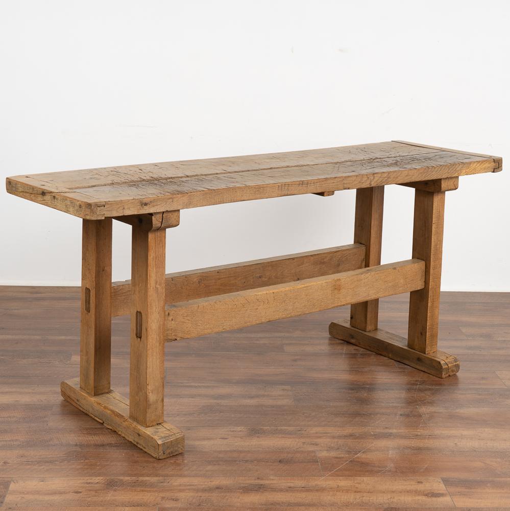 The strong appeal of this rustic console table comes from the well worn top reflecting generations of use.
It originally served as a work table, resulting in the worn dark patina with deep gouges, scrapes, stains, gnarls and old cracks.
This