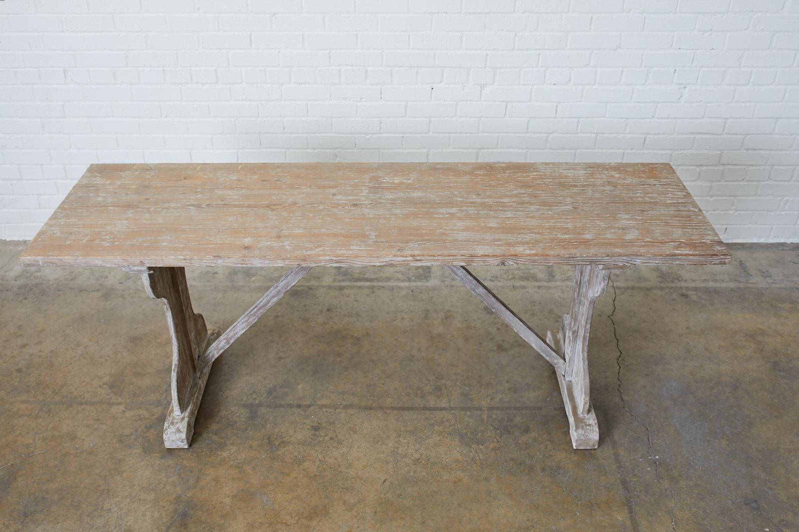 Rustic 20th century country French painted pine farmhouse table or console having trestle legs. Beautifully crafted with a washed or painted finish giving it an aged patina full of character and charm. This table is dining height and could be used
