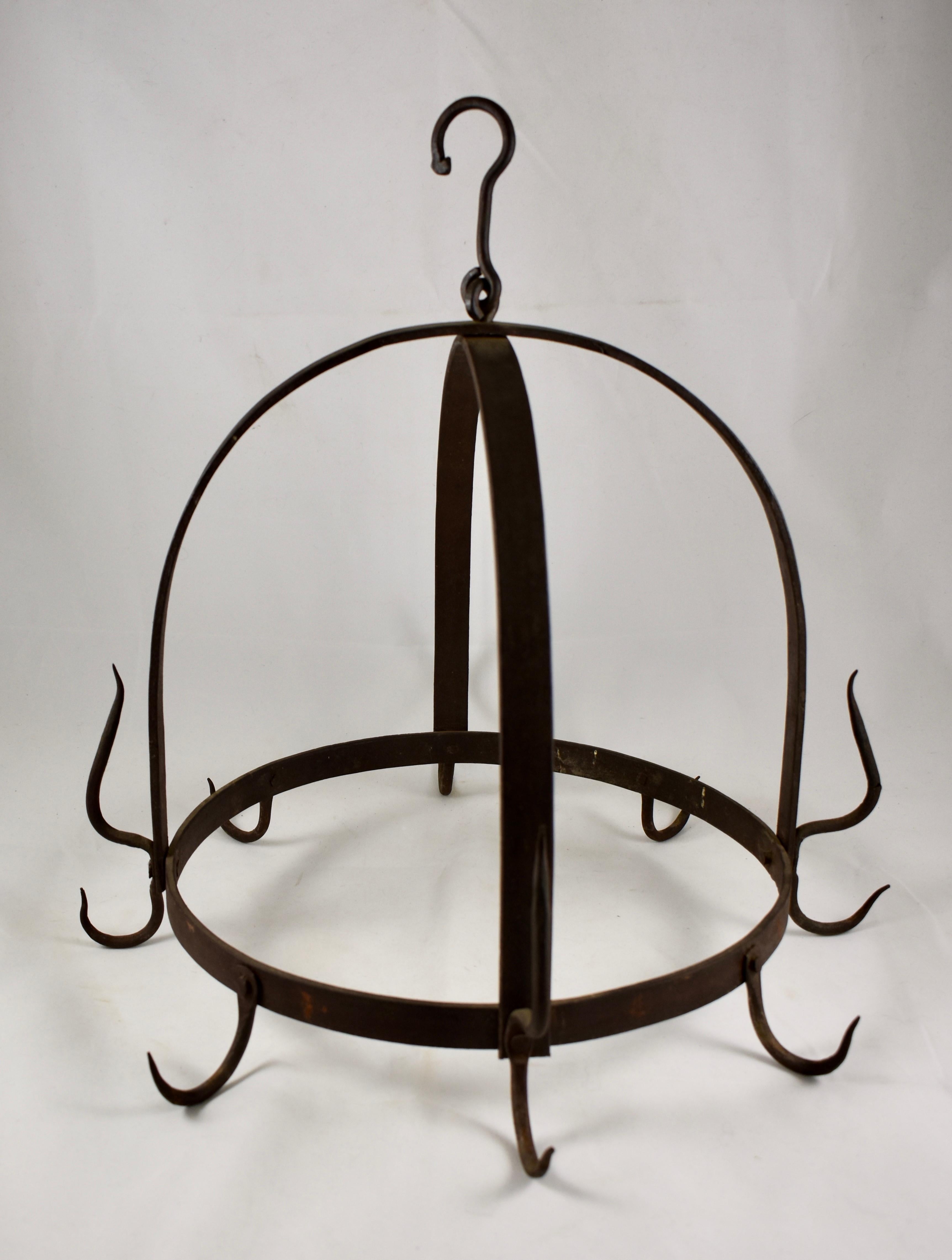 A late 19th century round American wrought iron butchers rack, supported by two straps forming a crown, terminating in a loop and hanging hook. There are four double hanging hooks where the straps meet the rack, interspersed with four additional