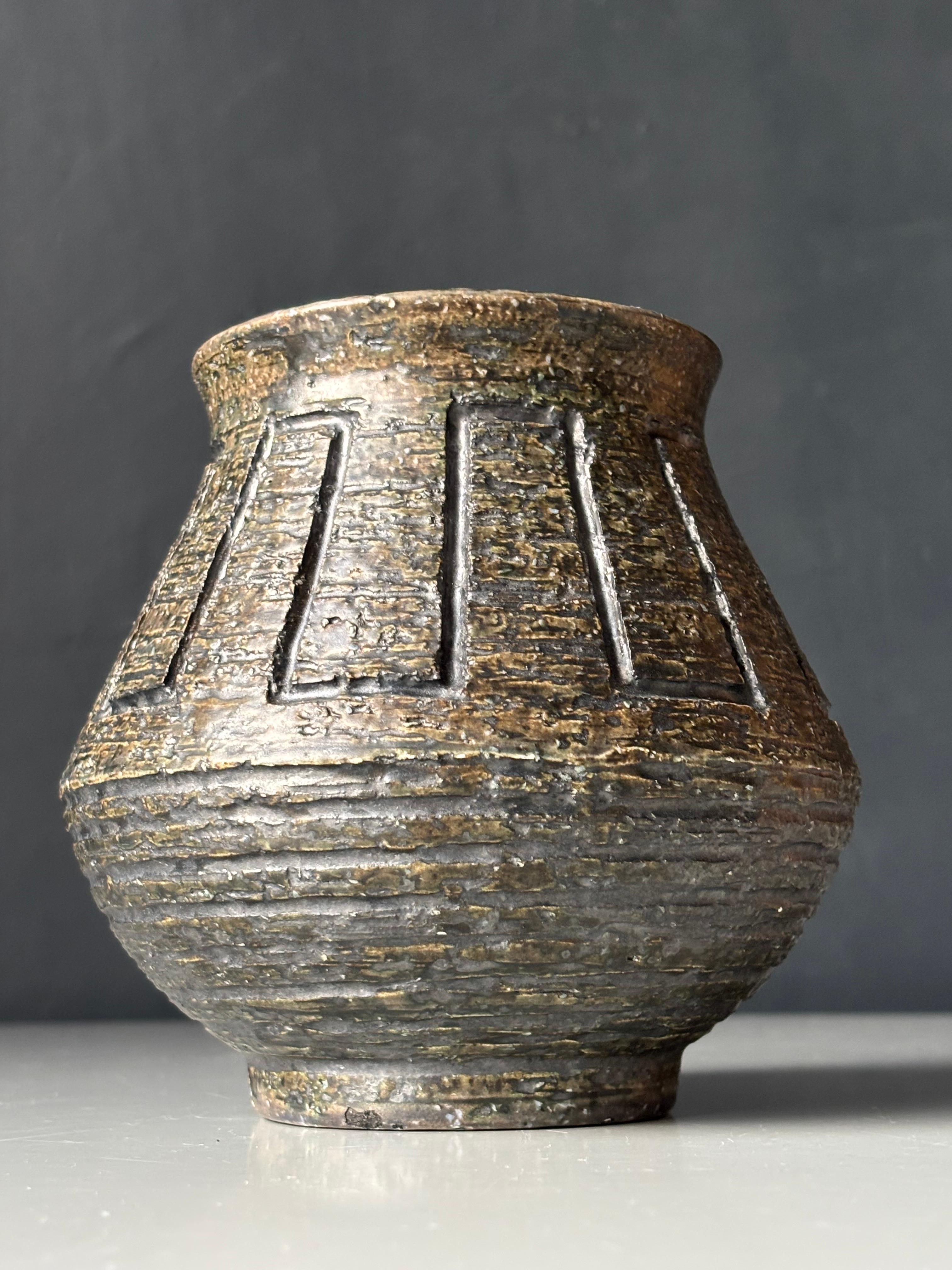 Vaso a urna brutalista a forma di barile realizzato a mano in chamotte di colore grigio scuro con smalto verde oliva Sage liscio e lucido all'interno. Decorazioni geometriche intagliate a mano nella parte superiore e linee verticali nella parte
