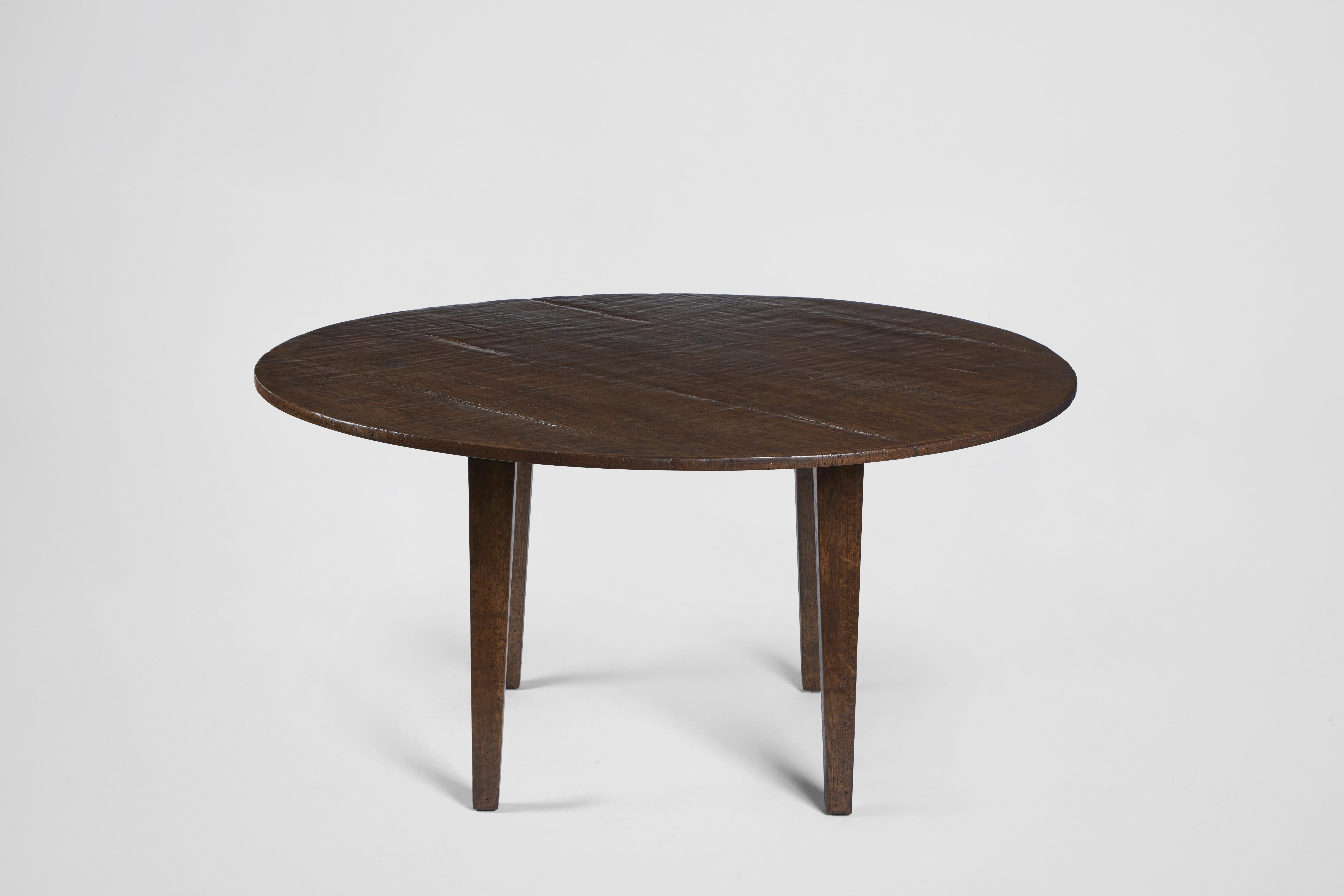 The classic round dining table meets old world beauty with this unique custom finish. The table's rustic finish highlights the natural grain and beauty of the wood for an old world, lived in feel. Features a plank style round tabletop and tapered