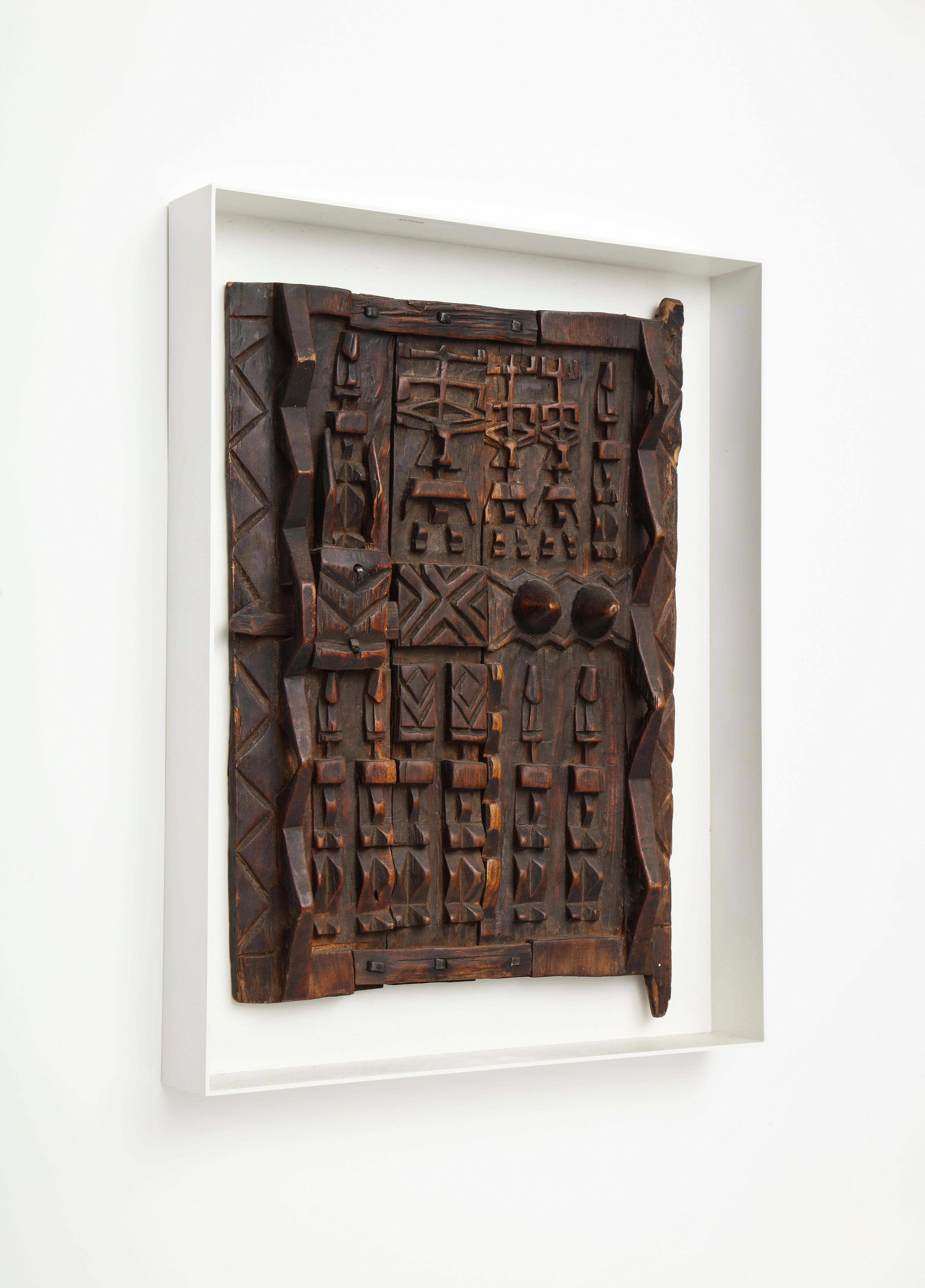 Door panel in the style of a Dogon Tribe granary door panel, carved wood. Mounted in custom painted metal shadow box frame.

The Dogon, subsistence farmers who hold ancient animist beliefs, are one of central Mali's ethnic groups. In the 15th