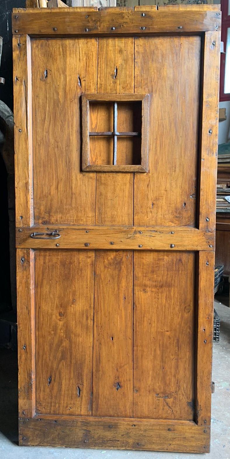 Ancient rustic door with nails, hand-built in solid poplar wood, still maintains the original window and irons, has a right-hand push opening, smooth on the back and without frame (it was mounted on the wall), hand-built in the late 19th century par