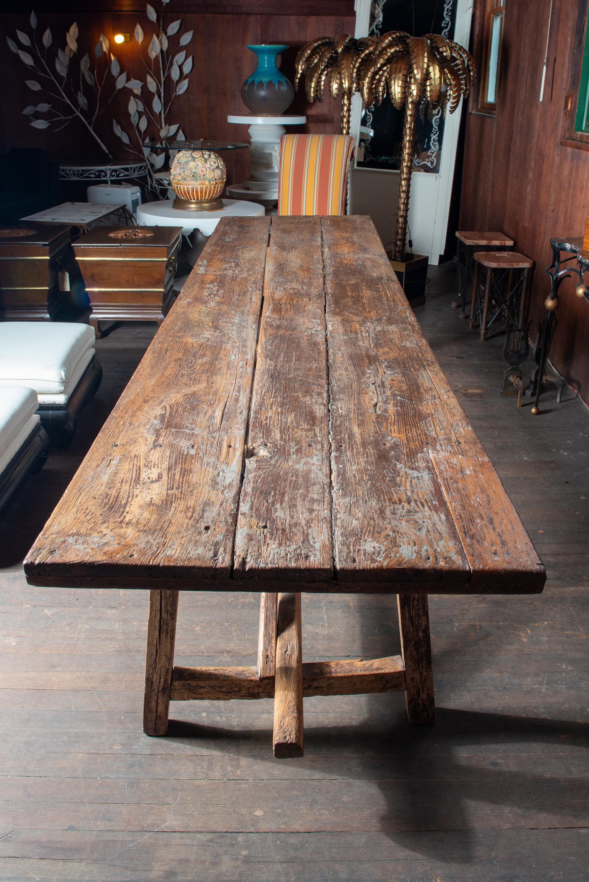 A stunning rustic dining farm table from the Netherlands. It is a Dutch style trestle construction with angled stretchers. The table top is formed by three long thick hardwood planks. The table depth of 31