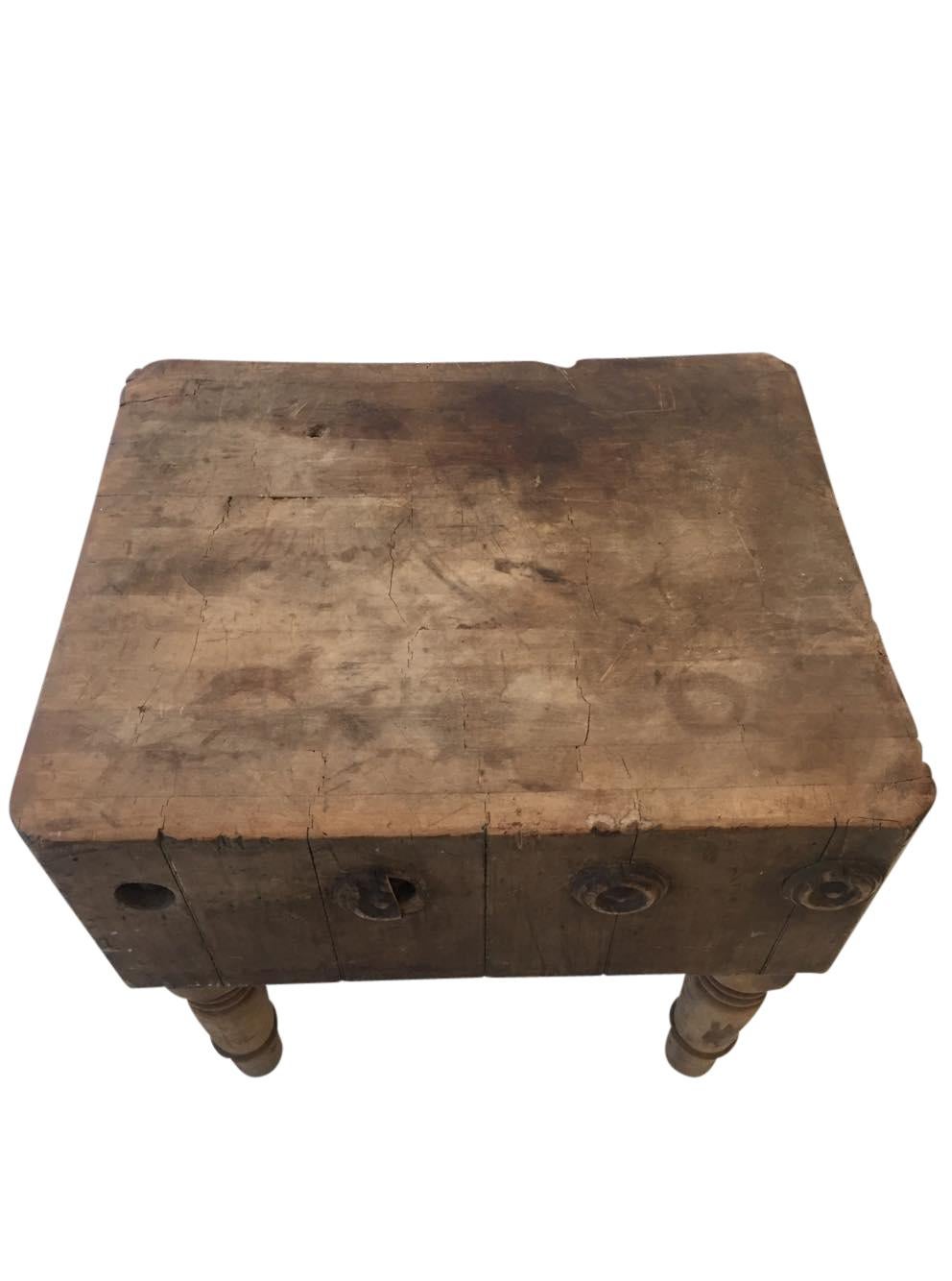 Robust authentic antique chopping block from the early 20th century. Salvaged North American kitchen accessory from market butcher in the northern midwest. Heavy duty maple with original tapered turned legs and markings.