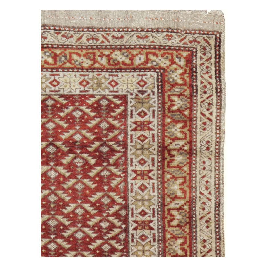 An antique Persian Kurd throw rug handmade during the early 20th century in shades of red and cream with an overall rustic appeal with its flat-weave Kilim ends and braided fringes.

Measures: 3' 10