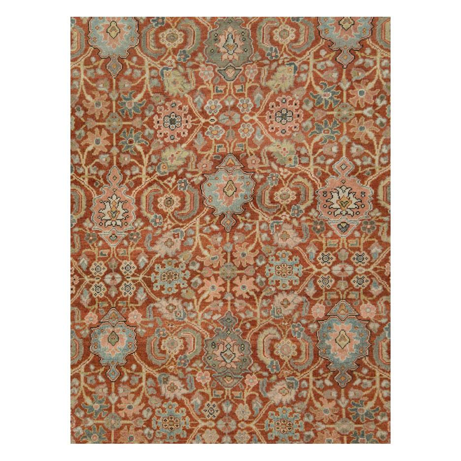 A rustic antique Persian Mahal room size carpet handmade during the early 20th century with a decorated rust-red field enclosed by a greyish green to khaki green border.

Measures: 9' 4