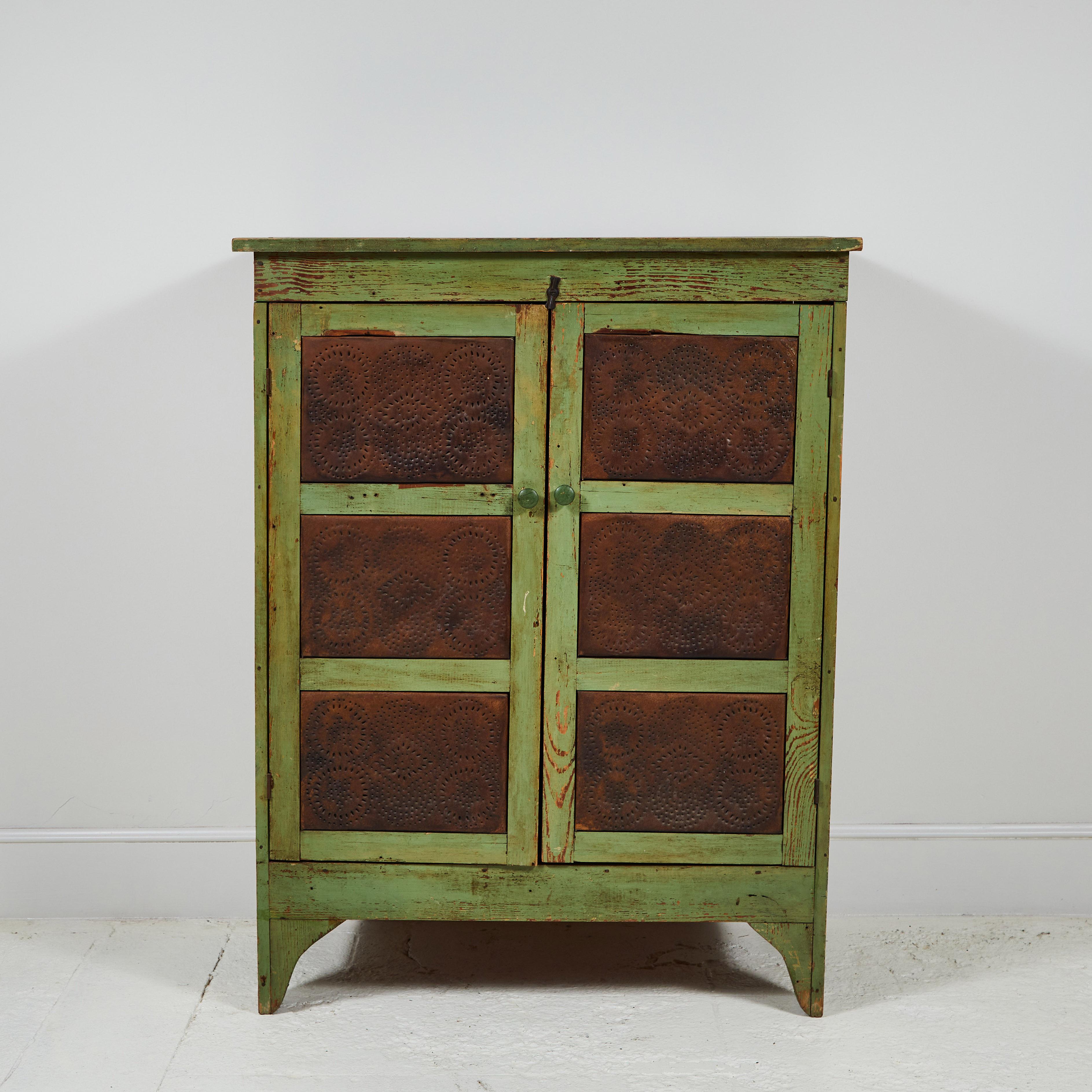 Rustic Early American green painted pie safe. Inside the two doors perforated metal doors offers two shelves.