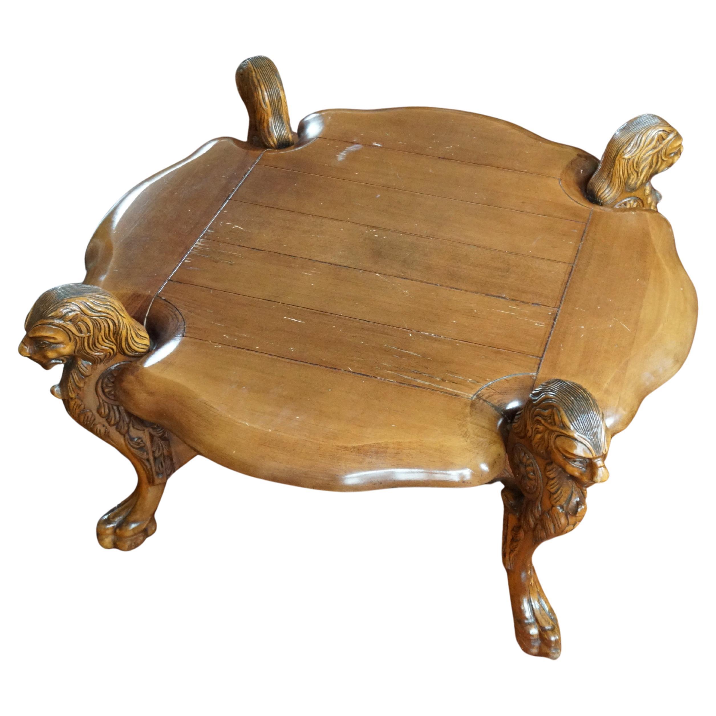 A rare carved coffee table from France or Italy, circa 1940s, crafted in solid wood with four sculptural lion heads and claw feet. This impressive piece combines rustic elegance with neoclassical refinement, offering the perfect balance between