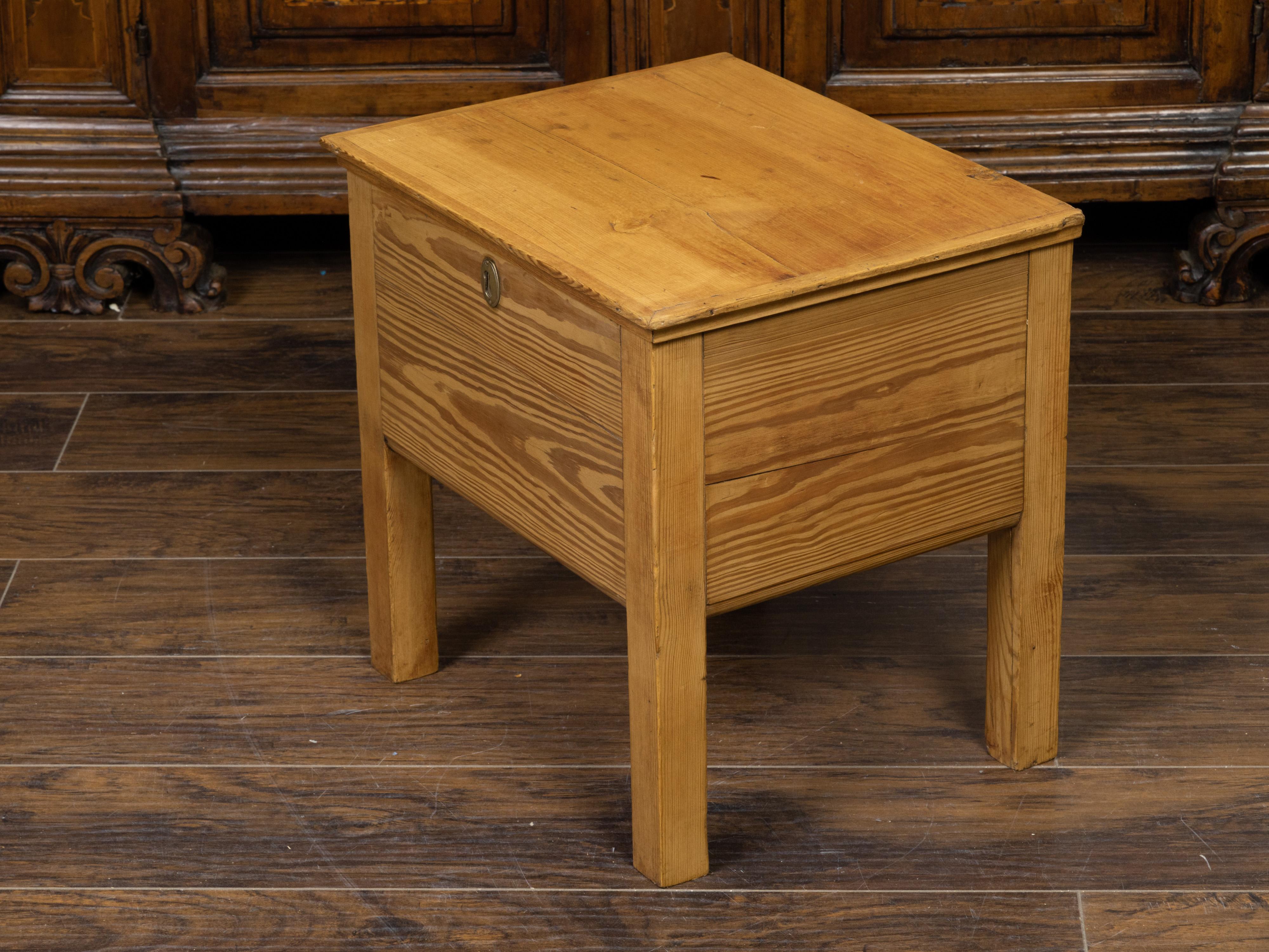A rustic English pine box on legs from the early 20th century, with brass escutcheon. Created in England during the early years of the 20th century, this pine box features a rectangular hinged lid that lifts up to reveal a convenient storage space.