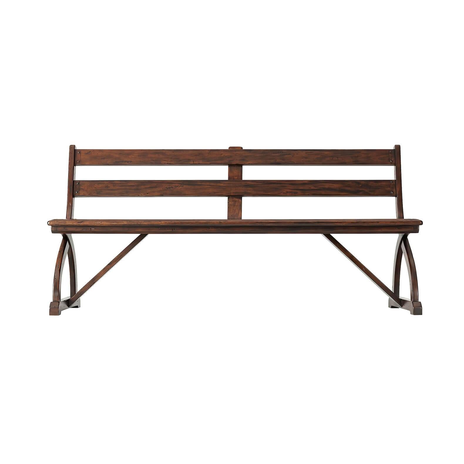 An English country antiqued mahogany bench, the slatted ladder back above a planked seat with a molded edge, on wishbone supports with sleigh bases and stretcher supports. Inspired by a 17th century original.
Dimensions: 72