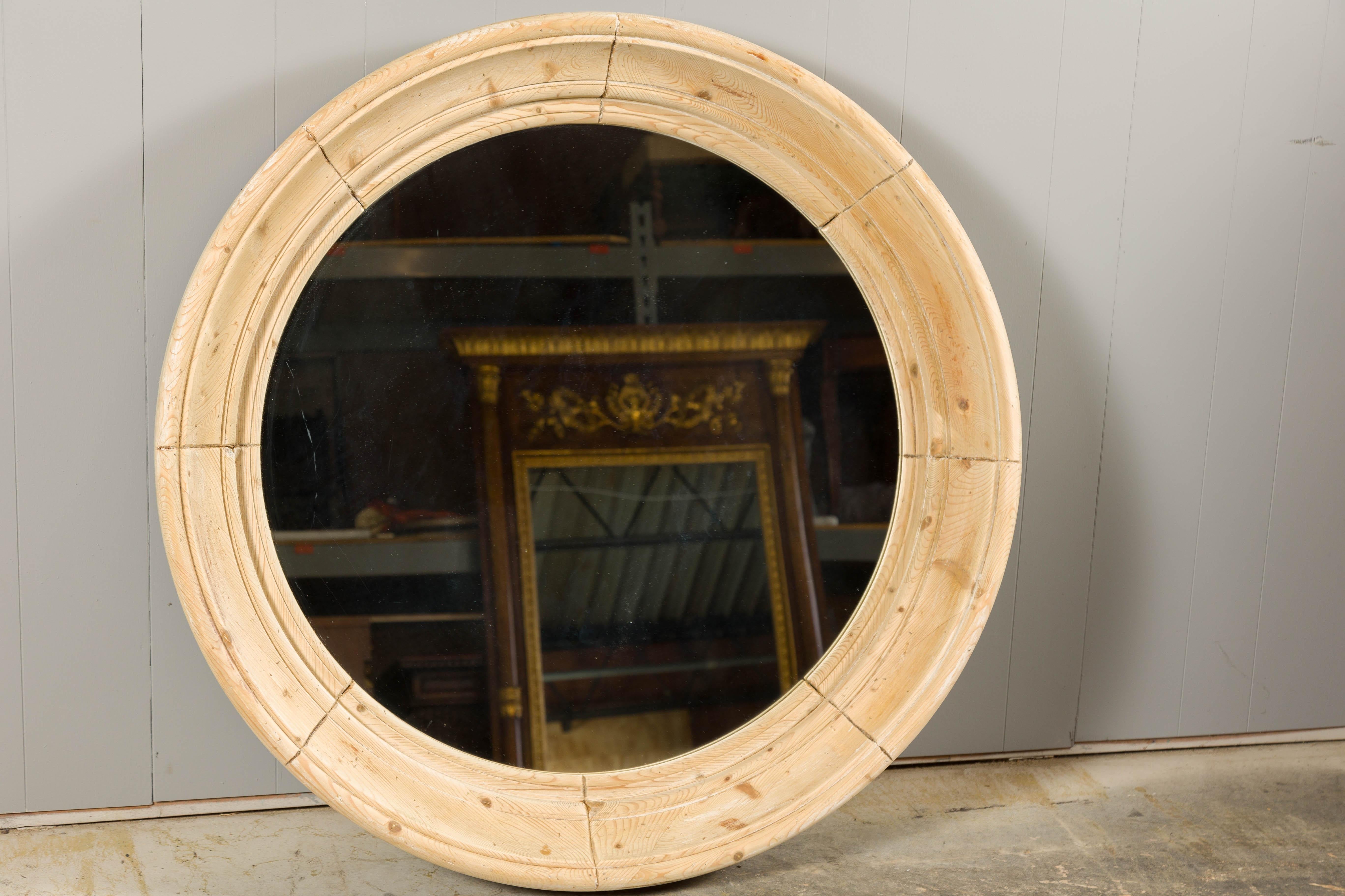 An English vintage Midcentury natural pine round bullseye mirror with in-curving frame and molded accents. Enhance your space with the rustic charm of this English vintage Midcentury bullseye mirror. Crafted from natural pine, this round mirror
