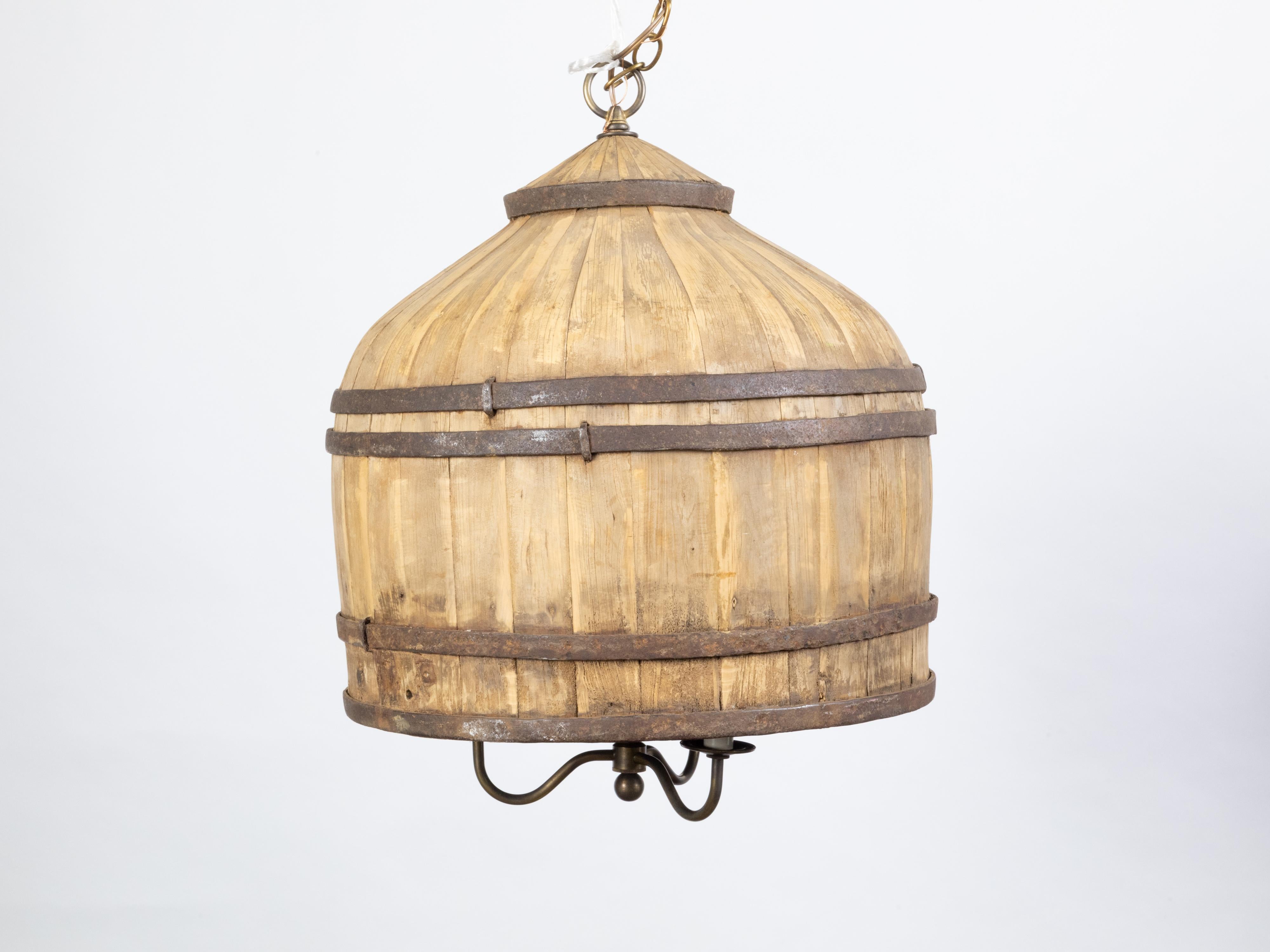 An English vintage wooden barrel light fixture from the mid 20th century, with three arms. Created in England during the midcentury period, this rustic light fixture features a wooden barrel strengthened with metal braces, securing three scrolling