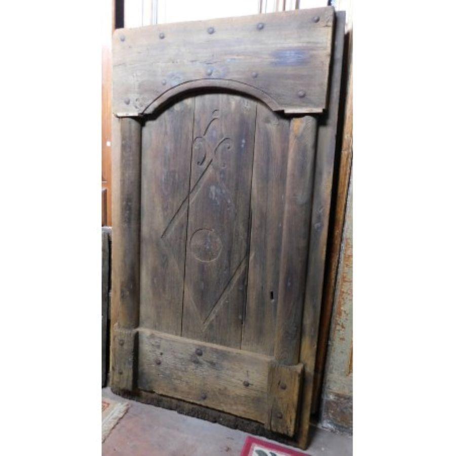 Ancient antique rustic entrance door, made with dark chestnut wood slabs, hand carved with columns and mountain symbols, made in the 19th century in northern Italy.
Typically rustic of the Italian mountain valleys, fantastic in a cabin or a rustic