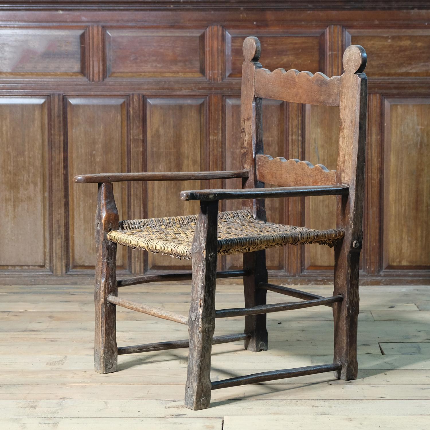 An exceptional rustic folk art chair in oak with a woven seat. In untouched condition, it has endless charm and character. Large size but not too dominating. Very similar in construction to the popular Irish sugan chair, but this example is likely