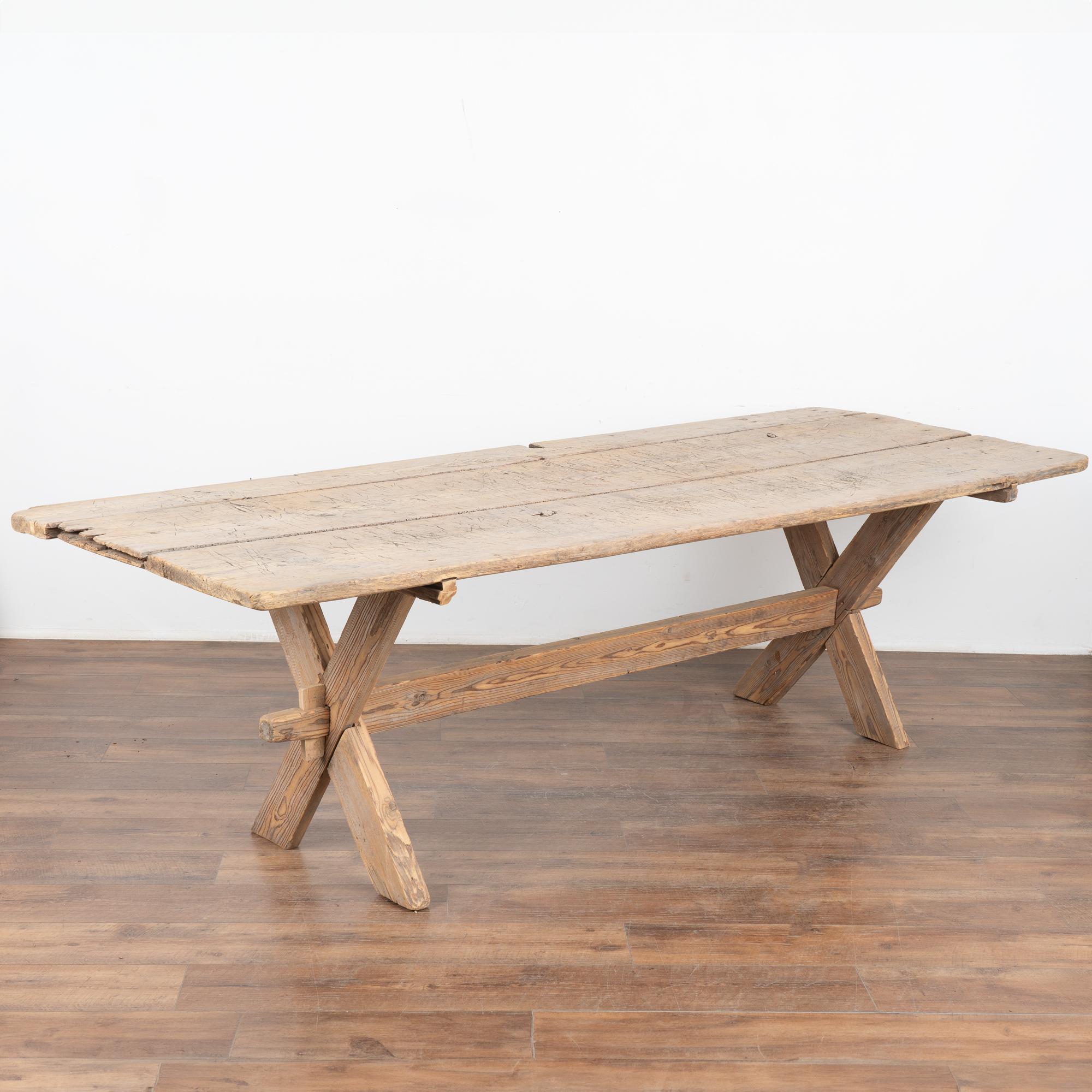 This farmhouse dining or kitchen table has European country charm thanks to the traditional X-stretcher base.
The natural pine has been distressed through generations of use, adding a weathered depth to the character of the table. The many