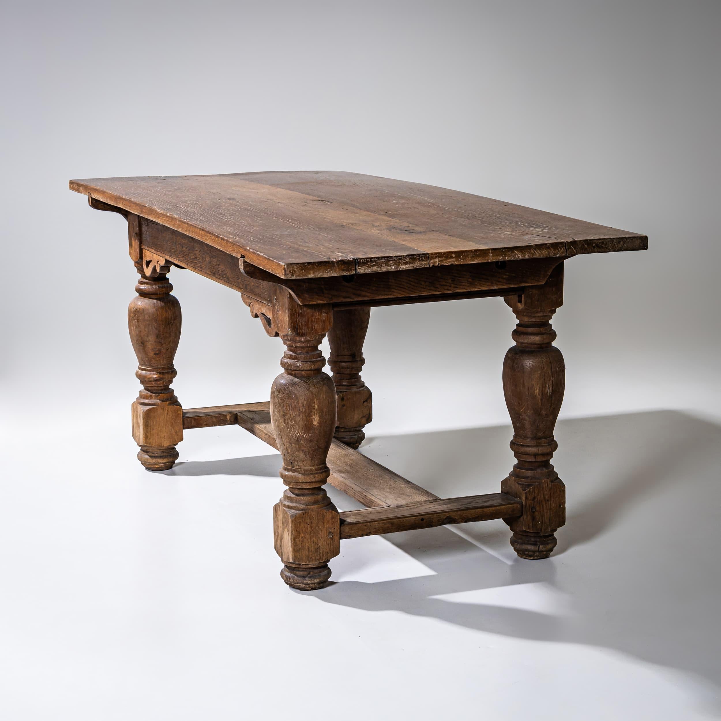 Table de salle à manger rectangulaire en chêne avec des pieds en balustre et une entretoise en forme de H entre les pieds. Les tabliers sont unis et ornés de consoles ornementales façonnées aux angles.